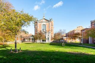 Exclusieve loft in het Groen Kwartier, gelegen op de voormalige site van het Militair Hospitaal — een oase van rust midden in de stad, met een uitzonderlijke bereikbaarheid en op wandelafstand van de hippe Zurenborgwijk. In de onmiddellijke omgeving vindt u een supermarkt, een gezellige bakker, het luxe hotel August bij horende spa en de prachtige kapel als centrum van de authentieke paviljoenen, waardoor deze locatie werkelijk alles te bieden heeft.<br /><br />De loft, met een bewoonbare oppervlakte van ca 285 m², bevindt zich op de eerste en tweede (hoogste) verdieping van één van de monumentale paviljoenen van de site. Het appartement werd in 2014 volledig uitgetekend door B-architecten. <br />U betreedt het gebouw via de gelijkvloerse verdieping, waar een privatieve en elegante trappenhal u naar het eerste verdiep leidt.<br /><br />Binnenin wordt u verwelkomd door een indrukwekkende leefruimte met een uitzonderlijke plafondhoogte en kamerhoge raampartijen die zorgen voor een overvloed aan natuurlijk licht. De ruimte, afgewerkt met een prachtige houten vloer, wordt op een subtiele manier onderbroken door een kastenblok die tevens een gashaard en een bureauruimte integreert — een perfecte combinatie van warmte, comfort en functionaliteit.<br /><br />De luxueuze keuken, uitgerust met Miele-toestellen, straalt verfijning en tijdloze elegantie uit dankzij het Carara marmeren werkblad. Alle moderne voorzieningen zijn aanwezig: een combi-stoomoven, heteluchtoven, vaatwasser, inductiekookplaat, koelkast en diepvriezer.<br /><br />Een absolute troef is het terras van ca 30 m², waar u het grootste deel van de dag van de zon kunt genieten dankzij de Zuidelijke oriëntatie.<br /><br />De trap zit verstopt in een catchy bibliotheekkast of omgekeerd. Hierlangs bereikt u de bovengelegen verdieping met vier slaapkamers. De hoofdslaapkamerbeschikt over op maat gemaakte dressingkasten en een lavabo. De slaapkamers kunnen gebruikmaken van de stijlvolle badkamer, voorzien van een vrijstaand ligbad, inloopdouche en dubbele lavabo. Een apart toilet biedt extra comfort.<br /><br />Daarnaast is de hal op de eerste verdieping voorzien van een berging met aansluiting voor wasmachine en droogkast, alsook een gastentoilet en een ingemaakte vestiarekast.<br /><br />Tot slot zijn er drie garageboxen beschikbaar, optioneel bij te kopen aan €50.000 per unit, exclusief registratiebelasting.<br /><br />De loft maakt deel uit van een beschermd monument — voor meer informatie over de rechtsgevolgen hiervan kunt u terecht op www.onroerenderfgoed.be.
