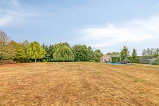 Tussen het groen in Zwevezele, op een riant domein van 10.997 m², biedt deze instapklare eigendom uit 2006 een uitzonderlijk totaalpakket voor wie riant wil wonen én professioneel wil ondernemen. De locatie garandeert rust en privacy, gecombineerd met een vlotte aansluiting richting Torhout, Roeselare en de E403. <br /><br />Het huis verrast door een indrukwekkende lichtinval, doordachte ruimtes en een hoogwaardige afwerking. Het gelijkvloers omvat een royale leefruimte met sfeervolle haard, een volledig uitgeruste leefkeuken met bijkeuken en koelcel, een bureau, drie slaapkamers en een ruime badkamer. Boven bevindt zich een extra woongedeelte — voorzien van een leefruimte, keuken, zonneterras, badkamer, dressing en twee extra slaapkamers. Deze indeling leent zich ideaal voor kangoeroewonen, een gastenverblijf of een praktijk.<br /><br />Buiten treft u een hoogwaardig aangelegde tuin waar rust en privacy centraal staan. Het uitnodigende zwembad, de jacuzzi en de sfeervolle vijver vormen samen het hart van het domein, met op de achtergrond een prachtig, vrij uitzicht over de omliggende velden. Het  bijgebouw — compleet ingericht met een sauna en inloopdouche — tilt het comfort op eigen terrein naar een nog hoger niveau. Een heerlijke plek om in volledige discretie te ontspannen en van het buitenleven te genieten.<br /><br />Voor zelfstandigen of ondernemers zijn de logistieke voorzieningen ongewoon uitgebreid op eigen terrein: een ruime hoofdloods, een tweede loods met dubbele doorrijpoort, overdekte opslagruimtes, een dubbele garage en drie garageboxen. Bovendien is de eigendom toekomstgericht uitgerust met een milieuvriendelijke warmtepomp, 58 zonnepanelen en 60.000 liter regenwateropslag.<br /><br />Bestuursmaatregelen in het maatregelenregister: nee