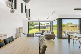 Deze vrijstaande nieuwbouwwoning, opgeleverd in 2025, combineert modern wooncomfort met een doordachte indeling en uitzonderlijk energiezuinige prestaties (EPC: -1 kWh/m²/jaar).<br /><br />De woning is gelegen op een ruim perceel van 1.034 m² en beschikt over een bewoonbare oppervlakte van ca. 207 m². Dankzij de aangename leefruimtes en praktische indeling biedt ze volop ruimte en comfort voor het hele gezin.<br /><br />Op het vlak van energiezuinigheid is de woning uitgerust met een warmtepomp en zonnepanelen. In de leefruimte en slaapkamer is airconditioning aanwezig. Voor de overige slaapkamers zijn de nodige voorzieningen reeds getroffen, zodat ook hier eenvoudig airconditioning kan worden geïnstalleerd.<br /><br />De woning wordt verkocht onder het stelsel van de registratierechten. Indien aan de wettelijke voorwaarden is voldaan, bedraagt het tarief 2%.<br /><br />Indeling:<br />Op het gelijkvloers bevindt zich een lichtrijke leefruimte met aansluitend een praktische bureauruimte, een open keuken voorzien van alle hedendaags comfort, een aanpalende ruime berging (+-16m2) met aparte inkom en een gastentoilet.<br /><br />Op de verdieping bevinden zich drie volwaardige slaapkamers, een stijlvolle badkamer uitgerust met zowel een ligbad als een ruime inloopdouche, en een tweede afzonderlijk toilet.<br /><br />De ruime tuin is zuidwest georiënteerd, achteraan bevindt zich nog een grote tuinberging (+-40m2). Deze ruimte is zeker ook geschikt als atelier, hobbyruimte, berging of opslagplaats.<br /><br />Buitengewone kenmerken:<br />- Nieuwbouwwoning<br />- EPC:-1kWh/m2j<br />- Aankoop mogelijk onder (2%) registratierechten<br />- Zonnepanelen<br />- Airco<br />- Warmtepomp<br />- Domotica<br />- Vloerverwarming<br />- 2 aparte toiletten<br />- Ruime tuinberging<br />- Vergunning voor plaatsen carport