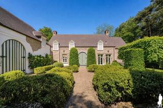 <p>Op een <strong>absolute toplocatie in het prestigieuze Kapellenbos</strong>, aan de Franselei 55, bevindt zich deze <strong>uitzonderlijke villa in kasteelhoevestijl</strong> op een <strong>residentieel perceel van ca. 5.700 m²</strong>. De ligging combineert <strong>uitstekende bereikbaarheid</strong> met <strong>volledige rust, privacy en groenbeleving</strong><span>.<br /><br /></span><strong>Indeling gelijkvloers</strong><br />De villa wordt bereikt via een <strong>monumentale kassei-oprijlaan</strong> en verwelkomt u in een <strong>ruime inkomhal</strong> met vestiaire en gastentoilet. Rechts bevinden zich twee <strong>stijlvolle leefruimtes met open haard</strong> (ca. <strong>55 m²</strong>) en zicht op de tuin. Links situeren zich de <strong>eetkamer</strong> (ca. <strong>20 m²</strong>) en de <strong>ruime eet-leefkeuken</strong> (ca. <strong>25 m²</strong>) met <strong>natuurstenen werkbladen, kookeiland en kwalitatieve toestellen</strong>, en met <strong>directe connectie naar terrassen en tuin</strong>. Aansluitend is er een <strong>volwaardige bijkeuken/wasplaats met douche</strong>.</p>
<p><strong>Indeling eerste verdieping</strong><br />De nachthal met vide geeft toegang tot <strong>vier slaapkamers en drie badkamers</strong>. De <strong>master bedroom</strong> (ca. <strong>25 m²</strong>) beschikt over een <strong>dressing en badkamer ensuite</strong>. De overige slaapkamers meten ca. <strong>18 m²</strong>, <strong>16 m²</strong> en <strong>14 m²</strong>. Eén van de badkamers is uitgerust met een <strong>sauna</strong>.</p>
<p><strong>Indeling tweede verdieping</strong><br />De tweede verdieping omvat een <strong>vijfde slaapkamer</strong> (ca. <strong>20 m²</strong>) met <strong>badkamer ensuite</strong>, ideaal als <strong>gastensuite of tienerkamer</strong>.</p>
<p><strong>Bijkomende ruimtes</strong><br />Een aparte zij-ingang geeft toegang tot een <strong>bureelruimte</strong> (ca. <strong>22 m²</strong>), een <strong>sportkamer</strong>, een <strong>logeerkamer/conciergerieruimte met badkamer</strong> en een <strong>dubbele inpandige garage</strong>, wat dit eigendom ook geschikt maakt voor <strong>praktijk of kantoor aan huis</strong>.</p>
<p><strong>Tuin</strong><br />De <strong>fraai aangelegde parktuin</strong> biedt <strong>volledige rust en privacy</strong> en is ingericht met <strong>strakke haagstructuren, volwassen bomen, een grote vijver, meerdere zonneterrassen</strong> en een <strong>eikenhouten bijgebouw</strong>. Een <strong>poort naar de achtergelegen dreef</strong> versterkt het exclusieve domeinkarakter.</p>
<p><strong>Bijzonderheden</strong><br /><strong>Absolute topligging in Kapellenbos</strong>, <strong>perceel ca. 5.700 m²</strong>, <strong>kasteelhoevestijl</strong>, <strong>monumentale oprijlaan</strong>, <strong>open haard</strong>, <strong>kwalitatieve leefkeuken</strong>, <strong>5 slaapkamers en 4 badkamers</strong>, <strong>sauna</strong>, <strong>bureau- en praktijkmogelijkheden</strong>, <strong>dubbele inpandige garage</strong>, <strong>bijgebouw</strong>, <strong>parktuin met vijver</strong>, <strong>uitstekende privacy</strong>.</p>
