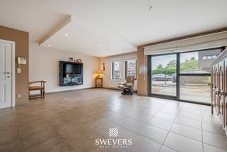 Voor meer info en foto’s, surf naar www.swevers.be – Dit instapklare gelijkvloerse appartement in het centrum van Zolder combineert een ruime indeling met aangenaam wooncomfort. Met een bewoonbare oppervlakte van 120 m², drie slaapkamers en een privatieve tuin rondom is dit een ideale woning voor wie comfortabel en gelijkvloers wil wonen. Het appartement maakt deel uit van een verzorgd gebouw uit 2007 en beschikt bovendien over een ondergrondse autostaanplaats en een kelderberging. Via de inkomhal bereikt u de ruime leefruimte van bijna 52 m², waar woonkamer en eetkamer naadloos in elkaar overvloeien. Dankzij de royale oppervlakte geniet u hier van alle vrijheid om een gezellige zithoek en een volwaardige eethoek in te richten. Aansluitend bevindt zich de praktische keuken met voldoende werk- en opbergruimte. De nachthal geeft toegang tot drie slaapkamers van respectievelijk 13,26 m², 9,51 m² en 9,07 m². Deze ruimtes zijn perfect inzetbaar als slaapkamer, bureau, hobbykamer of logeerkamer. De badkamer is uitgerust met zowel een bad als een douche. Daarnaast is er een aparte toiletruimte en een handige berging. Buiten geniet u van een tuin rondom het appartement, met een terras aan de voorzijde en een overdekt terras van 9,61 m² aan de achterzijde. De zuidwestgerichte achtertuin biedt volop zon in de namiddag en avond en vormt een aangename plek om tot rust te komen. Extra troeven zijn de zonnepanelen, rolluiken, parlofoon, lift en de vlotte verbinding tussen de ondergrondse parking en het appartement. Scholen, winkels, restaurants, openbaar vervoer en ontspanningsmogelijkheden bevinden zich op wandel- of korte rijafstand. Ook de snelwegen zijn snel bereikbaar. Voor meer informatie, bel 011 255 155. Bron bewoonbare oppervlakte: EPC – verslag.