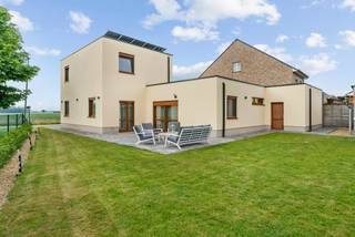 Recente woning voorzien van alle moderne comfort die, met uitzondering van enkele muren, volledig nieuw is opgetrokken en afgewerkt van 2018 - 2024. Hier is gekozen voor kwalitatieve materialen en de nieuwste technieken waardoor de woning zeer energiezuinig is (A-label).<br />De woning beschikt over 4 slaapkamers waarvan 2 op de gelijkvloerse verdieping, badkamer op de gelijkvloerse verdieping, hyper uitgeruste keuken, ruime woonkamer, berging, apart toilet, inpandige garage en fraai aangelegde tuin met bijgebouw en terras.<br /><br />U betreedt de woning via de centrale inkomhal met apart toilet. Hier heeft u toegang tot de vierde slaapkamer of bureauruimte. Ideaal voor zelfstandigen die klanten thuis wensen te ontvangen aangezien zij de privéruimtes niet moeten betreden. <br />Voorts bevindt zich de woonkamer met vooraan zicht op de weilanden en veel lichtinval. Van hieruit kan u de moderne keuken betreden die volledig is ingericht met Siemens/Miele toestellen (oven, microgolf, koffietoestel, stoomoven, vaatwasmachine, koelkast, diepvriezer, inductievuur). Deze is ook ingericht met veel opbergkasten en ruim kookeiland. Naast de keuken vindt u een extra bergruimte terug met toegang naar de kelder. Verder bevinden er zich op de gelijkvloerse verdieping een extra slaapkamer, alsook de zeer praktische badkamer. De badkamer is volledig betegeld en geïnstalleerd met inloopdouche, ligbad, toilet en dubbele lavabo. <br /><br />De eerste verdieping voorziet de woning van 2 extra ruime slaapkamers. Vanuit de master bedroom heeft u een prachtig uitzicht over de uitgestrekte weilanden. <br /><br />Bovendien beschikt de woning over een inpandige garage met automatische poort.<br /><br />Bijzonderheden:<br />- rustige locatie vlakbij de autosnelweg naar Antwerpen en Eindhoven, creche, kleuter -en lagere <br /> school, winkels etc.<br />- Energiezuinige woning met zonnepanelen en vloerverwarming (label A, E-peil 51)<br />- Komende 4 jaar vrijgesteld van betaling onroerende voorheffing<br />- Domotica<br />- Hoogwaardige afwerking