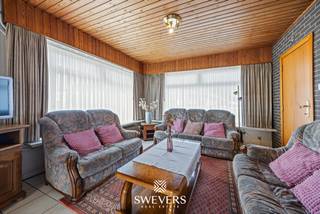 Voor meer info en foto’s, surf naar www.swevers.be – Deze rustig gelegen bungalow aan Heidestraat 42 in Leopoldsburg biedt een praktische gelijkvloerse indeling, drie slaapkamers en een ruim zuidgericht perceel van 810 m². De open bebouwing dateert van 1970, heeft een bewoonbare oppervlakte van 134 m² en is toe aan een opfrissing. Ideaal voor wie de woning stap voor stap naar eigen smaak wil vernieuwen. Via de inkomhal bereik je de leefruimte van 28,86 m² met living en eetkamer. Aansluitend bevindt zich de keuken van 13,05 m², die grenst aan de veranda en zo een fijne verbinding met de buitenruimte vormt. Verder is er een afzonderlijk toilet. De drie slaapkamers meten 13,34 m², 9,58 m² en 8,03 m² en bieden mogelijkheden als hoofd-, kinder-, logeer- of werkkamer. Ook de badkamer bevindt zich op het gelijkvloers, waardoor comfortabel wonen zonder trappen mogelijk is. Extra bergruimte vind je in de garage van 20 m² en de kelder van 16,18 m². Het ruime, zuidgerichte perceel biedt bovendien heel wat mogelijkheden voor een zonnige tuin en gezellige buitenruimte. Openbaar vervoer, winkels, restaurants en ontspanning bevinden zich op bereikbare afstand. Een interessante woning voor wie gelijkvloers wonen wil combineren met ruimte en renovatiemogelijkheden. Voor meer informatie, bel 011 255 155. Bron bewoonbare oppervlakte: EPC – verslag.