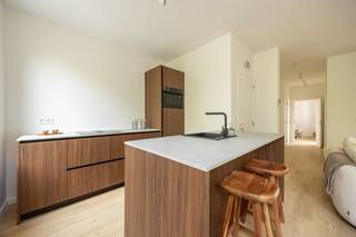 <p><span> </span></p><p><span>Strak gerenoveerd, energiezuinig én helemaal instapklaar: dit appartement van ca. 67 m² op de eerste verdieping heeft het allemaal. Je krijgt een heerlijk lichte leefruimte met open keuken, twee slaapkamers en een stijlvolle badkamer, afgewerkt in warme houttinten. En dat in een fijne buurt van Berchem, met het Brilschanspark en natuurgebied Wolvenberg op wandelafstand.</span><span> </span></p><p><span> </span></p><p><span>Lichte leefruimte met warme leefkeuken</span></p><p><span>Je komt het appartement binnen in de centrale hal, van waaruit je meteen doorloopt naar de leefruimte vooraan. Hier is lekker veel plaats voor een ruime zithoek en een grote eettafel. Het kamerbrede raam trekt veel natuurlijk licht binnen en de warme parketlaminaat loopt mooi door in het hele appartement. De zwarte pvc-ramen met driedubbele beglazing zorgen voor een strak accent én extra comfort.  De open keuken past perfect in dat plaatje. De donkerbruine houtlook kasten geven de ruimte warmte, terwijl het lichte werkblad en het donkere kraanwerk het geheel strak houden. Het grote kookeiland met spoelbak doet tegelijk dienst als gezellige ontbijtogen: ideaal om er een paar barkrukken bij te schuiven. Ook praktisch is alles voorzien, met Samsung-toestellen zoals een combioven en vaatwasser en een Elica inductievuur met ingebouwde afzuiging. </span></p><p><span> </span></p><p><span>Twee slaapkamers &amp; stijlvolle badkamer</span></p><p><span>Via de lange hal ga je naar de twee slaapkamers. De eerste is leent zich perfect als kinder-, logeer- of werkkamer. De master bedroom biedt ruim plaats aan een dubbel bed en extra kasten. Ook hier zorgen de grote ramen met driedubbele beglazing voor natuurlijk licht.  De badkamer sluit helemaal aan bij de rustige, hedendaagse stijl van het appartement. Je hebt er een ruime inloopdouche met grijze betegeling en regendouche, een zwevend houtlook meubel met witte opbouwwastafel en donker geborsteld kraanwerk. Het toilet is netjes geïntegreerd in dezelfde ruimte. In de hal vind je bovendien nog een aparte berging van met aansluiting voor je wasmachine. Hier zitten ook de elektrische Ariston-boiler en de Vaillant-omvormer van de privatieve zonnepanelen netjes uit het zicht. </span></p><p><span> </span></p><p><span>Groen wonen in Berchem</span></p><p><span>Hier combineer je stad en groen zonder moeite. Het Brilschanspark en het mooie natuurgebied Wolvenberg liggen op wandelafstand, en ook sportcentrum Het Rooi is vlakbij. Voor je dagelijkse boodschappen vind je supermarkten enkele straten verder. Zin in een koffie, restaurant of wat winkels? Dan sta je zo in Oud-Berchem, de Pulhofwijk of Groenenhoek.   </span></p><p><span>Ook energetisch zit je hier bijzonder goed. Het appartement haalt EPC A en is voorzien van privatieve zonnepanelen, elektrische verwarming, driedubbele beglazing en ventilatiesysteem C+. Voeg daar conforme elektriciteit en een asbestveilig attest aan toe en je hebt een appartement waar je zonder grote werken meteen je dozen kunt uitpakken. </span></p><p><span> </span></p><p><span> </span></p>
