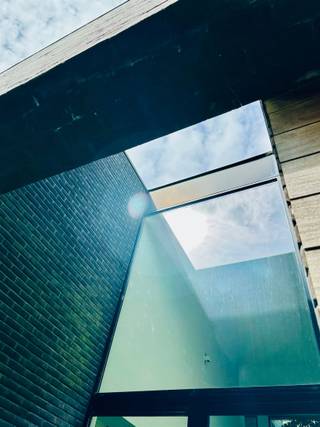 Bent u op zoek naar een unieke woonst waar licht, ruimte en privacy samenkomen? Lees dan zeker verder!Deze ruime open villa van 15 x 15 meter is gelegen op een prachtig perceel van 1.132 m² in een idyllische, landelijke omgeving. Met een gunstig EPC-label B voldoet de woning ruimschoots aan de huidige energetische normen. De volgroeide, aangelegde tuin biedt volop privacy, terwijl de N16 en E17 zorgen voor een uitstekende bereikbaarheid.Bij aankomst springt de indrukwekkende voorgevel meteen in het oog. De imposante voordeur van 5,35 meter hoog en 2,20 meter breed bevindt zich op 16 meter van de straatkant en is strategisch verscholen in een lichtkoker achter een volle muur. Een slim geplaatst raam van 1 x 6 meter voorkomt inkijk en biedt vanuit de woning een panoramisch zicht op de groene voortuin. Binnen zorgen de open indeling en twee vides voor een uitzonderlijk ruimtegevoel. De leefruimte van 12 x 6 meter heeft een plafondhoogte van 5,35 meter en wordt overspoeld door daglicht dankzij de indrukwekkende raampartijen. De 3 meter diepe oversteek van zijgevel en dak fungeert als natuurlijke zonwering, waardoor de woning ook op warme dagen aangenaam koel blijft. De open leefkeuken beschikt over een groot keukeneiland, ruime kasten en grote plafondhoge ramen. Op het gelijkvloers loopt de authentieke Belgische blauwe hardsteen drempelloos door van de inkomhal tot het terras, waardoor binnen en buiten één geheel vormen.De bovenverdieping straalt warmte uit dankzij de Vlaamse eiken parketvloer. De master bedroom sluit aan op een indrukwekkende glaswand van 15 meter lang en 2,55 meter hoog, gevolgd door een dressing en badkamer met dubbele lavabo, toilet en ruime inloopregendouche. Een praktische wasberging en comfortabele logeerkamer vervolledigen deze verdieping. U hoeft dus nooit meer met zware wasmanden de trap op en af! De woning is uitgerust met lage-temperatuurvloerverwarming via een hoogwaardige Weishaupt-condensatieketel. Twee afzonderlijke circuits en thermostaten laten toe om boven en beneden onafhankelijk te verwarmen.Ook de tuin is een absolute troef, met 29 volwassen bomen, diverse hagen, fruitbomen en een walnotenboom. De regenwaterput van 10.000 liter is aangesloten op twee toiletten en kan ook op de wasmachine worden aangesloten. De dubbele inpandige garage biedt plaats aan twee wagens naast elkaar.Wilt u zelf de unieke sfeer, ruimte en architectuur van deze villa ervaren? Neem dan zeker contact met ons op voor een bezoek!