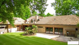<p><strong>Riante energiezuinige villa met binnenzwembad en maximale privacy</strong></p>
<p>Op zoek naar luxe, ruimte en rust? Deze exclusieve villa, gelegen op een residentieel en rustig perceel van 2.477 m², biedt het allemaal. Met een bewoonbare oppervlakte van maar liefst 540 m² geniet je hier van comfortabel en energiezuinig wonen in een groene, discrete omgeving.</p>
<p>De woning werd gebouwd in 2006 en is voorzien van alle hedendaagse comfort. De ruime woonkamer met open leefkeuken baadt in natuurlijk licht en vormt het hart van het huis. De gehele gelijkvloerse verdieping is voorzien van gepantserd glas. Verder beschikt de villa over 5 volwaardige slaapkamers en 4 badkamers – ideaal voor grotere gezinnen of wie graag gasten ontvangt.</p>
<p>Voor ontspanning hoef je de deur niet uit: het luxe binnenzwembad zorgt voor een permanent vakantiegevoel. Ook thuiswerken wordt een plezier dankzij de grote kantoorruimte. Bovendien is er een aparte studio, perfect als gastenverblijf, praktijkruimte of voor inwonende hulp.</p>
<p>Buiten geniet je van een overdekt terras en een prachtig aangelegde tuin die volledige privacy garandeert. De dubbele garage maakt het plaatje compleet.</p>
<p>Bij het betreden van deze riante en energiezuinige villa komt u via de inkomhal meteen in de ruime leefruimte terecht. De woonkamer met gezellige zithoek en gashaard vloeit naadloos over in de eetplaats en de open leefkeuken, die voorzien is van alle hedendaags comfort – een ideale plek voor wie graag kookt en gasten ontvangt.</p>
<p>Een stijlvolle glazen wand scheidt de woonkamer van het binnenzwembad. Hoewel het zwembad momenteel buiten gebruik is, zijn alle technieken aanwezig om dit eenvoudig opnieuw in werking te stellen. Momenteel wordt de ruimte gebruikt als fitnessruimte, maar ze biedt ook andere mogelijkheden zoals wellness of hobbyruimte. Aansluitend bevinden zich een technische ruimte en een welnessgedeelte met sauna, douche en toilet. Een trap leidt hier naar een grote polyvalente ruimte op de verdieping, uitgerust met airconditioning en momenteel ingericht als kantoor.</p>
<p>Op het gelijkvloers is ook een ruime dubbele garage met toegang tot de kelder. Tussen de keuken en garage bevindt zich een tweede trap die leidt naar een studio, bestaande uit twee slaapkamers en een badkamer met douche, lavabo en toilet – ideaal als gastenverblijf of voor inwonende hulp.<br /><br />Vanuit de centrale inkomhal vertrekt een derde trap naar de bovenverdieping, waar u de masterbedroom vindt, uitgerust met parketvloer, airconditioning en gashaard. De master beschikt over een aanpalende dressing en een eigen badkamer met bad, douche en toilet. Daarnaast zijn er nog twee extra slaapkamers met parket en een aparte badkamer met ligbad, lavabo en toilet. Een gastentoilet is eveneens voorzien op het gelijkvloers.</p>
<p><strong>Buitenleven in alle comfort</strong></p>
<p>Grenzend aan de woonkamer bevindt zich een ruim overdekt terras, uitgerust met elektrische rolschermen en terrasverwarming – ideaal om het hele jaar door van buiten te genieten. Een tweede terras ligt aan het binnenzwembad. De aangelegde tuin rondom de woning biedt volledige privacy en rust. Verder beschikt het domein over een carport en een professioneel alarmsysteem.</p>
<p>Een unieke combinatie van ruimte, luxe en rust. Klaar om jouw nieuwe thuis te worden?</p>
