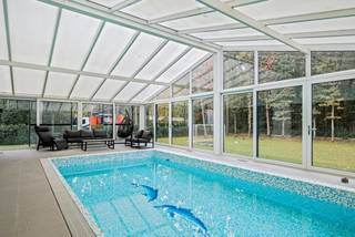Deze unieke villa is gelegen in een groene en residentiële wijk van Schoten.<br /><br />Bij het betreden van de woning word je meteen gegrepen door de majestueuze inkomhal, waar een elegante Spaanse trap je blik omhoog trekt. De open leefruimte baadt in natuurlijk licht dankzij grote raampartijen die een naadloze verbinding maken met de prachtig aangelegde tuin.<br />De moderne keuken – ruim en functioneel – is een plek waar koken een beleving wordt. Dankzij de aangrenzende berging blijft alles netjes opgeborgen. Hier woon je in een huis dat ademt: licht, openheid.<br />Achter glas, discreet geïntegreerd in de tuinzijde van de woning, vind je het volledig afgesloten binnenzwembad. Of het nu zomer of winter is, hier geniet je in alle privacy van ontspanning met zicht op het groen.<br />Op het gelijkvloers vind je ook:<br />- Een gezellige bureauruimte voor wie thuis werkt<br />- Een gastentoilet en een aparte wasruimte – praktisch en doordacht<br /><br />Op de eerste verdieping ontdek je vier royale slaapkamers, elk met overvloedig daglicht. Drie slaapkamers beschikken over een eigen badkamer, wat zorgt voor comfort en privacy – ideaal voor grotere gezinnen of logerende gasten.<br /><br />De kelderverdieping verrast met een luxueuze wellness- en ontspanningsruimte. Denk aan een privé fitness, biljartkamer, sauna met aparte douche en een sfeervolle hobbyruimte. <br /><br />Bijzonderheden: <br />- Een zee van ruimte en licht in elke kamer<br />- Grote raampartijen met zicht op groen<br />- Binnenzwembad met tuinzicht voor elk seizoen<br />- Zonnepanelen met 10.000 kWh batterijopslag<br />- Energiezuinige warmtepomp en regenwaterrecuperatie<br />- Automatisch tuinsproeisysteem op grondwater<br />- Garage voor twee wagens<br />- Vier ruime slaapkamers, waarvan drie met en-suite badkamer<br />- Volwaardige wellnessruimte in de kelder