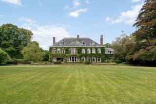 Te midden van een prachtig parklandschap, verscholen in rust en privacy, bevindt zich het uitzonderlijke domein Haezenveld te Kapellen. Oorspronkelijk gebouwd in 1938 door de grootvader van de huidige eigenaars, ademt dit eigendom een zeldzame combinatie van authenticiteit, elegantie en verfijnd wooncomfort.<br /><br />Het hart van het domein wordt gevormd door de prestigieuze villa. Een statige inkomhal leidt naar ruime ontvangstruimtes, waar hoogwaardige materialen zoals authentiek parket en sierlijke afwerkingen warmte en karakter brengen. De eetkamer met hoge plafonds en brede deuren, de prachtige bibliotheek met open haard en ingemaakte kasten, en het royale salon met meerdere zithoeken vormen samen een setting die zowel stijlvol als functioneel is.<br />Vanuit de villa geeft een overdekt terras zicht op de fraai aangelegde parktuin. Praktische voorzieningen zoals een keuken met aparte eethoek, wasplaats en kelders voor wijn en voorraad onderstrepen de doordachte indeling.<br />Op de eerste verdieping bevinden zich vier ruime slaapkamers, elk met verfijnde details en en-suite badkamers. Eén kamer beschikt bovendien over een open haard en balkon. Aanvullend zijn er drie kinderkamers en een hobbyruimte, eveneens bereikbaar via een buitentrap. De zolderverdieping biedt bijkomende kamers; logeerruimtes, personeelsvertrekken of bergruimtes.<br /><br />Naast de hoofdvilla maakt een gerenoveerde conciërgewoning (2019) (deels verhuurd) deel uit van het domein, aangevuld met drie garages, stallen en bergruimtes. <br /><br />Een domein met uitstraling:<br />De omgeving van de villa is adembenemend. De vijver, Franse tuin, eeuwenoude bomen en uitgestrekte weilanden creëren een sfeer van rust en harmonie. <br />Het domein beschikt daarnaast over een te renoveren zwembad en tennisveld, evenals een moestuin met bijhorende kassen.<br /><br />De essentie van exclusiviteit:<br />Haezenveld is een uitzonderlijk eigendom dat klassieke elegantie koppelt aan hedendaags comfort. Het domein straalt discretie, grandeur en authenticiteit uit en behoort daarmee tot de meest bijzondere residenties van Noord-Antwerpen.<br /><br />Haezenveld is een levend kunstwerk; een schilderij waarin perspectieven en kleuren mee veranderen met de uren van de dag en de seizoenen. Paarden, schapen, zwanen, wilde eenden, reeën en talloze vogels maken deel uit van het decor. Muren die begroeid zijn met een meer dan tachtig jaar oude wilde wijnstok versterken de authenticiteit. <br />Enkel natuur, stilte, wooncomfort en discretie omarmen dit domein<br /><br />Buitengewone kenmerken:<br />Landgoed van ca. 100.000m²<br />Privatieve oprijlaan<br />Parking voor 10 wagens<br />Villa Haezenveld, Conciërgewoning (2019), garages (plaats voor 5 wagens), <br />Park met vijver, eeuwenoude bomen, rododendrons, gazons en bospercelen<br />Vier weiden voor paarden en schapen<br />Moestuin met serre voor bloemen, groenten en fruit<br />Zwembad en tennisbaan (te renoveren)<br />Absolute rust en volledige privacy, zonder zichtbare buren of geluidsoverlast<br />Goede bereikbaarheid, open baar vervoer, scholen, winkels in de omgeving