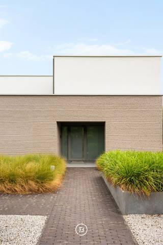 In een rustige en groene omgeving in Brakel bevindt zich deze moderne villa, waar hedendaagse architectuur, comfort en verfijnde afwerking samenkomen. Grote raampartijen brengen overvloedig natuurlijk licht binnen en zorgen voor een sterke verbinding met de zorgvuldig aangelegde buitenomgeving. Het zwembad, poolhouse en de verschillende terrassen maken van de tuin een bijzonder aangename plek om te ontspannen en te genieten van de omgeving.<br /><br />Bij het betreden van de woning komt men in een ruime inkomhal met vestiaire en gastentoilet. De leefruimtes zijn bijzonder lichtrijk en beschikken over grote raampartijen die een directe connectie maken met de tuin en het zwembad. De ruime leefruimte omvat een zithoek en eetplaats en sluit naadloos aan op de volledig uitgeruste keuken. De open indeling en doordachte zichtlijnen zorgen voor een aangename en vloeiende woonbeleving.<br /><br />Op het gelijkvloers bevindt zich tevens een slaapkamer met aansluitende badkamer en directe toegang tot het terras. De verdieping omvat de masterbedroom met ruime dressing en ensuite badkamer, voorzien van een dubbele douche, wastafel en ligbad met ver zicht. Daarnaast is er een polyvalente ruimte die kan worden ingericht als fitness, bureau, polyvalente ruimte of bijkomende slaapkamer.<br /><br />De buitenomgeving vormt een belangrijke troef van de eigendom. De aangelegde tuin beschikt over een ingebouwd zwembad van 9 op 4 meter, een stijlvol poolhouse en verschillende terrassen. Hierdoor zijn er doorheen de dag verschillende plaatsen om te genieten van de zon, de tuin en de rust.<br /><br />Een bijkomende mogelijkheid is de aankoop van de achterliggende fruitgaard van 4.911 m². Deze vormt een waardevolle uitbreiding van de eigendom en biedt verschillende mogelijkheden. Zo kan men er in alle rust genieten van de bestaande fruitgaard, extra privacy en groen creëren, of ruimte voorzien voor het houden van dieren zoals paarden of schapen. Voor wie vooral op zoek is naar extra ruimte en een nog sterker landelijk karakter, biedt de fruitgaard een bijzonder mooie aanvulling op de villa.<br /><br />Ook technisch is de woning bijzonder compleet uitgerust, met onder meer vloerverwarming via warmtepomp, 50 zonnepanelen, thuisbatterij, laadpaal, ventilatiesysteem D en airconditioning. De woning beschikt over een EPC-label A en combineert daarmee hedendaags wooncomfort met een energiezuinig karakter.