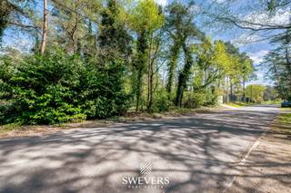 Voor meer info en foto’s, surf naar www.swevers.be – In de prestigieuze villawijk van Viversel in Heusden-Zolder wacht een uitzonderlijke bouwgrond van 27a40 op haar nieuwe eigenaar. Gelegen aan het rustige Sacramentspad, midden in een bosrijke omgeving, biedt dit perceel een ongeziene kans op exclusief en groen wonen. De oriëntatie laat bovendien volop ruimte voor een doordacht ontwerp dat speelt met lichtinval en openheid. Hier komt elke vierkante meter tot zijn recht, met de natuur als uw constante buur. De prachtige groengordel van bomen verhoogt niet alleen de esthetiek van de woning, maar biedt ook extra beschutting en privacy. Het vormt een waardevolle buffer die het wooncomfort aanzienlijk vergroot en de natuur tot in de tuin brengt. De ligging in een woonparkgebied garandeert maximale rust en privacy. Daarnaast is de ligging uiterst gunstig: op 2 km van de E313, met scholen, natuur, recreatie en openbaar vervoer op wandel- of fietsafstand. Voor meer informatie, bel 011 255 155.