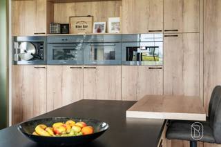 Exclusieve nieuwbouwwoning met 5 slaapkamers, 360 m² woonoppervlakte, toekomstgerichte voorzieningen, en genietend van een prachtig zicht! Bent u op zoek naar een uitzonderlijk ruime en kwalitatieve woning waar comfort, luxe en toekomstgericht wonen centraal staan? Deze in 2023 gebouwde woning biedt maar liefst 360 m² bewoonbare oppervlakte op een perceel van 1.235 m² en werd technisch bijzonder doordacht uitgevoerd.Indeling gelijkvloers: ruime inkomhal, afzonderlijke ruimte ideaal als bureau, apart toilet en een zeer ruime, lichtrijke leefruimte. Aansluitend bevindt zich de luxueuze, volledig geïnstalleerde keuken met hoogwaardige Miele-toestellen, waaronder wijnkoeler, stoomoven, oven, vaatwasser en espressomachine. Verder is er een grote wasruimte met douche en waskoker vanuit de badkamer boven. De inpandige garage biedt plaats aan één wagen, technische installaties en extra stockage.Eerste verdieping: vier slaapkamers, apart toilet en een royale ruimte voorzien voor de inrichting van een wellnessbadkamer, nog volledig af te werken volgens eigen smaak en materiaalkeuze.Zolderverdieping: ingerichte vijfde slaapkamer met verdere afwerkingsmogelijkheden. De voorziene liftschacht loopt door tot deze verdieping.Technisch is de woning bijzonder compleet met vloerverwarming op het gelijkvloers en de eerste verdieping, ventilatiesysteem type D, brede deuropeningen en een liftschacht met bekabeling voor de plaatsing van een inpandige lift.Buiten geniet u van een ruim terras, tuin en meerdere parkeerplaatsen. Bovendien is er een vergunning voor een bijgebouw van 14 m².Een aantal ruimtes dienen nog naar eigen smaak worden afgewerkt, waardoor u zelf de gewenste materialen en inrichting kunt bepalen.Voor wie is dit pand ideaal?♦ Gezinnen die uitzonderlijk veel woonruimte zoeken.♦ Wie comfortabel én toekomstgericht wil wonen.♦ Wie een recente woning verder naar eigen smaak wil afwerken.Een unieke kans voor wie ruimte, kwaliteit en toekomstgericht wooncomfort wil combineren.Bezoek na afspraak met Immo Beguin, jouw vastgoedexpert sinds 2009.Meer info of bezoek via emmy@immobeguin.be