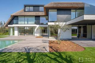 In een residentiële en rustig gelegen villawijk bevindt zich deze zeer hoogwaardige afgewerkte nieuwbouwvilla te koop. Gelegen op een prachtig zuidergericht perceel van 990m2 en voorzien van een heerlijk verwarmd zwembad.<br /><br />Gelijkvloers: via de riante voordeur verkrijgt men toegang tot de ruime inkomhal met ingemaakte vestiairekasten. Door de grote raampartijen geniet de woonkamer van zeer veel natuurlijk lichtinval en een prachtig zicht op de tuin. Aansluitend bevindt er zich een aparte bureauruimte met ingemaakte kasten. Via de woonkamer verkrijgt men toegang tot de magnifiek aangelegde tuin die voorzien is van een prachtig zwembad en een zonovergoten terras. De uitzonderlijk ruime keuken met eetplaats is eveneens zeer hoogwaardig afgewerkt en is voorzien van de meest luxeuze en kwalitatieve toestellen. Via de grote schuiframen heeft men toegang tot een overdekt terras met BBQ. Aanpalend is er een aparte wasruimte met aansluitingen voor een wasmachine en droogkast. De ruime garage geeft plaats aan 2 wagens en een golfcar.<br /><br />Eerste verdieping: open nachthal die toegang biedt tot de eerste 3 uitzonderlijk ruime slaapkamers, die elk voorzien zijn van een dressing. Tevens heeft elke slaapkamer een ensuite badkamer die zeer luxeus zijn afgewerkt.<br /><br />Tweede verdieping: hier bevinden zich de vierde en vijfde slaapkamer die eveneens voorzien zijn van ingemaakte kasten en beschikken over een eigen douchekamer. Daarnaast is er een extra bergruimte aanwezig.<br /><br />Deze villa heeft een ruime en praktische kelderverdieping, waar men uiterst veel bergruimte verkrijgt.<br /><br />Tevens is deze volledige villa uitgerust met de meest moderne technieken o.a warmtepomp met geothermie, allerlei domotica en een moderne lift.<br /><br />Verkoop onder registratierechten.<br /><br />Een bezoek ter plaatse wordt sterk aangeraden en is steeds mogelijk op afspraak!