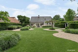 <p>Charmant wonen met een royale tuin. Dat willen we toch allemaal? Alleen… het is niet altijd zo makkelijk te vinden.</p>
<p><strong>Goed nieuws.</strong><br />Wat op het eerste gezicht al een ruime woning lijkt, blijkt in werkelijkheid nóg groter. Deze vrijstaande villa beschikt over maar liefst <strong>358 m² vloeroppervlakte</strong>, <strong>5 mogelijke slaapkamers</strong>, een afzonderlijk bureel én een <strong>zolderverdieping</strong>. Ruimte in overvloed dus, voor wonen, werken en leven.</p>
<p>Nieuw? Nee.<br />Maar wél perfect instapklaar, met alle potentieel om verder naar eigen smaak te verfijnen. Bij de bouw werd bewust gekozen voor duurzame en kwaliteitsvolle materialen: een natuurstenen vloer, eiken trap, massieve binnendeuren en parket. In 2023 werden bovendien <strong>zonnepanelen</strong> en een <strong>nieuwe verwarmingsketel</strong> geplaatst.</p>
<p>En wie goed kijkt, ziet dat de benedenverdieping al een stijlvolle make-over kreeg.</p>
<hr />
<h2>Indeling</h2>
<h3>Gelijkvloers</h3>
<p>Binnenkomen doe je in een royale inkomhal met overvloedige lichtinval en gastentoilet. Een statige binnenkomer die meteen de toon zet.</p>
<p>Via dubbele deuren stap je de woonkamer binnen. De grandeur loopt hier moeiteloos verder. Dankzij de grote raampartijen geniet je van uitzonderlijk veel licht en een panoramisch zicht op de tuin.</p>
<p>De tuin zelf beschikt over:</p>
<ul>
<li>
<p>Een ruim terras aansluitend aan keuken en woonkamer</p>
</li>
<li>
<p>Een omheind gedeelte voor dieren</p>
</li>
</ul>
<p>Verder vinden we op het gelijkvloers:</p>
<ul>
<li>
<p>Een volledig ingerichte keuken</p>
</li>
<li>
<p>Een badkamer</p>
</li>
<li>
<p>Een bureel</p>
</li>
<li>
<p>Een eerste slaapkamer (of speelkamer, hobbyruimte, extra kantoor — jij kiest)</p>
</li>
<li>
<p>Een praktische wasberging met aansluitingen voor was- en droogmachine</p>
</li>
<li>
<p>Een inpandige garage voor twee wagens</p>
</li>
</ul>
<hr />
<h3>Verdieping</h3>
<p>En dan zijn we er nog niet.</p>
<p>Op de bovenverdieping bevinden zich nog:</p>
<ul>
<li>
<p>4 (slaap)kamers</p>
</li>
<li>
<p>Een volledig uitgeruste badkamer</p>
</li>
<li>
<p>Een afzonderlijk toilet</p>
</li>
</ul>
<p>Twee slaapkamers beschikken bovendien over een eigen terras.</p>
<hr />
<h3>Zolder</h3>
<p>Als extra troef beschikt de woning over een ruime zolderverdieping. Ideaal als extra bergruimte, hobbyruimte of – mits verdere afwerking – perfect om nog bijkomende kamers te creëren.</p>
<hr />
<h2>Ligging</h2>
<p>Als kers op de taart ligt deze woning in een groene, rustige omgeving in een prestigieuze buurt van <strong><span><span>Merksplas</span></span></strong>.</p>
<p>Een ideale combinatie van ruimte, comfort en locatie.</p>