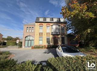 <br />In het centrum van Lochristi, verscholen tussen het groen, vindt u 1 van de mooiste parels van Lochristi. Het prachtig herenhuis op de hoek van de Burgemeester Vermeulenlaan en de N70 heeft een heuse renovatie ondergaan, met respect voor het historisch karakter.<br />Het pand is opgewaardeerd en voldoet volledig aan de hedendaagse normen met behoud van enkele prachtige authentieke elementen.<br />Op vandaag bestaat het herenhuis uit een handelsruimte op het gelijkvloers (huisartsenpraktijk) en 4 appartementen, waarvan dit appartement op de eerste verdieping, bereikbaar via lift of authentieke traphal.<br />Dit één slaapkamer appartementen dat eveneens geniet van een ruim terras (13m²) met mooi uitzicht.<br />Via de inkomhal heb je een apart toilet en daarna komt u in de ruime lichtrijke open keuken ingericht met kwalitatieve toestellen en deels afzonderlijke zitruimte. Het terras is toegankelijk via de zitruimte en slaapkamer met prachtig zicht op het groen.<br />Verder is er een ruime slaapkamer die toegang heeft naar de badkamer met inloopdouche en kast met lavabo en wasruimte.<br />Het E-peil van dit appartement is E50, deze is dan ook goed geïsoleerd en maakt gebruik van een warmtepomp.<br /><br />Dit luxueus appartement is volledig afgewerkt met verlichting én gordijnen.<br />Met andere woorden, een uniek, volledig instap klaar appartement in hartje Lochristi!<br /><br />Dit appartement geniet van een eigen autostaanplaats en daarnaast is er een fietsstalling voorzien.<br />Er is een lift aanwezig!<br /><br />Beschikbaar vanaf 1/11/2026<br /><br />Huurprijs: 960,00€ + 50,00€ alg kosten = 1010,00€/maand<br /><br />Interesse in dit appartement? Mail ons met uw naam EN telefoonnummer: info@loimmo.be<br />Wij contacteren U!