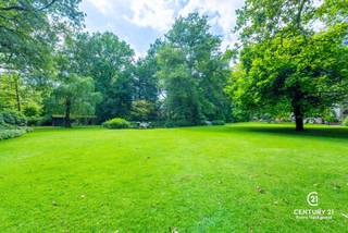 <p><strong>Karaktervol landhuis met prachtig aangelegde tuin, bijgebouw en extra naastliggend bouwperceel van ca 2077m² met verweven tuin optioneel bij aan te kopen – uniek woonaanbod op toplocatie</strong></p>
<p>In een residentiële en rustige omgeving wacht dit uitzonderlijk goed onderhouden landhuis op haar nieuwe bewoners. Gelegen op een royaal dubbel perceel met een schitterend aangelegde en volgroeide tuin, biedt deze eigendom een unieke combinatie van charme, ruimte en veelzijdigheid.<br /><strong>Bovendien geniet u van een uitstekende bereikbaarheid: op slechts 25 minuten rijden van zowel Eindhoven (NL) als Antwerpen (BE)</strong> – een ideale ligging voor wie centraal, maar toch in alle rust wil wonen.</p>
<p>Via de ruime inkomhal met gastentoilet en aparte bureauruimte betreedt u de sfeervolle leefruimte. De gezellige open haard, de brede raampartijen en de naadloze overgang naar de eetkamer zorgen voor een warme, huiselijke sfeer met overal zicht op de prachtige tuin. De volledig uitgeruste keuken is aangenaam ruim en beschikt over een aansluitende berging.</p>
<p>Op de eerste verdieping bevinden zich vier volwaardige slaapkamers en drie badkamers. De masterbedroom beschikt over een eigen inloopdressing, een royale badkamer én een privé-sauna – een ware wellnessbeleving aan huis.</p>
<p>Een bijzonder pluspunt is het multifunctionele bijgebouw, dat bestaat uit een ruime garage met drie poorten en meer dan voldoende opbergruimte. De bovenverdieping van dit gebouw is ingericht als hobbyruimte met een gezellige bar, douche en apart toilet – ideaal als gastenverblijf, atelier, of als zelfstandige ruimte voor inwonende tieners of hulp. Deze verdieping is bereikbaar via een aparte buitentrap.</p>
<p>De tuin is werkelijk een parel: aangelegd als een rustgevend park met vijvers, wandelpaadjes en idyllische zithoekjes vormt het geheel een oase van groen en stilte. Dit extra perceel biedt tevens potentieel voor wie toekomstgericht denkt aan bouwen of uitbreiden. Voor meer informatie over de villa met inbegrip van het optionele perceel verwijzen we u door naar onze eigen website.</p>
<p><strong>Kortom: een unieke kans voor wie op zoek is naar een karaktervol landhuis met veel ruimte, privacy, uitstekende bereikbaarheid en een uitzonderlijk mooie buitenomgeving.</strong></p>