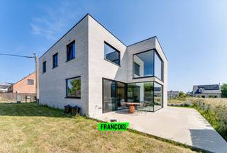 Deze moderne villa bevindt zich in de Snoekstraat, een doodlopende straat in een rustige en kindvriendelijke woonwijk te Vlissegem. Het strakke architecturale ontwerp, de overvloedige lichtinval en het open zicht op de omgeving zorgen voor een harmonieuze combinatie van comfort en hedendaagse elegantie.<br /><br />Via de inkomhal met gastentoilet kom je in de ruime leefruimte met grote keramische vloertegels. Woon- en eetgedeelte vloeien naadloos in elkaar over en vormen samen een gezellige, open ruimte. De moderne keuken — uitgevoerd in verfijnd houten maatwerk met een travertin marmeren werkblad en ingebouwde Miele-steamer — vormt het centrale punt van de woning. De aluminium ramen met glas-op-glas hoeken versterken het gevoel van openheid en zorgen voor een open blik op de zuidgerichte tuin met terras, een ideale plek om te genieten van rust en zon.<br /><br />Aansluitend vind je een koele berging, een ruime wasplaats met veel opbergruimte en een aparte bureauruimte, ideaal voor wie een rustige plek zoekt voor administratie of studie.<br /><br />Op de verdieping bevinden zich vier volwaardige slaapkamers, een dressing en een stijlvolle badkamer met inloopdouche, dubbele wastafel en badmogelijkheid. De nachthal biedt extra bergruimte en toegang tot een afzonderlijk toilet.<br /><br />Met een E-peil van 14 combineert de woning modern wooncomfort met optimale energie-efficiëntie. 15 zonnepanelen, vloerverwarming en een regenwaterput van 15.000 liter dragen bij aan een duurzaam en laag-verbruik leefklimaat. De oprit voor twee wagens maakt de praktische kant van de woning compleet.<br /><br />De bewoonbare oppervlakte stemt overeen met de nuttige oppervlakte zoals gekend bij het kadaster.<br /><br />Bent u op zoek naar een woning die rust, ruimte en comfort biedt? Neem dan snel contact op met Julien via julien@immofrancois.be of bel +32 471 74 25 41. <br /><br />