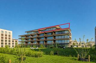 Dit uitzonderlijke dakappartement verwelkomt u via een stijlvolle inkomhal, voorzien van een gastentoilet en een praktische berging/wasplaats. De nachthal geeft toegang tot drie volwaardige slaapkamers, waaronder een riante master bedroom met een luxueuze en suite badkamer, uitgerust met een inloopdouche, ligbad, dubbele wastafel en toilet. Aansluitend geniet de master van een dressingruimte en directe toegang tot een terras van 14 m², een ideale plek om te genieten van het uitzicht.<br /><br />De twee overige slaapkamers delen een tweede, smaakvol ingerichte badkamer, voorzien van een enkel lavabomeubel en een inloopdouche. Doorheen het volledige appartement werd gekozen voor een hoogwaardige lichte steenparket voor een warme en tijdloze uitstraling. Via een smeedijzeren deur betreedt u de riante, lichtrijke leefruimte. Volledig geïnstalleerde leefkeuken met gezellige ontbijthoek en aansluitend bevindt zich de eetruimte, die uitgeeft op een tweede terras van 14 m².<br /><br />Het ruime salon met zithoek biedt directe toegang tot het zonnige terras van 21 m², waar u geniet van een prachtig uitzicht op het water en het omliggende groen.<br /><br />Verder beschikt het appartement over een kelderberging en zijn er twee autostaanplaatsen inbegrepen.<br /><br />Bijzonderheden:<br /><br />- Rustige en residentiële locatie<br />- Grote raampartijen met veel natuurlijke lichtinval<br />- De terrassen zijn half overdekt zodat u in alle seizoenen van het buitenleven kan genieten<br />- Vloerverwarming (warmtepomp)<br />- Lift<br />- Ondergrondse privatieve berging en twee autostaanplaatsen<br />- EPC A-label - 57 kWh/m² <br /><br />Vg - Gso - Vv - Gvkr - Gmo - Gworg