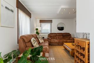 Voor meer info en foto’s, surf naar www.swevers.be – Aan de Schaapsweg 98 in Heusden-Zolder vind je deze ruime, instapklare woning op een perceel van maar liefst 1.404 m². De woning werd gebouwd in 1988 en kreeg doorheen de jaren verschillende verbeteringen, waaronder een vernieuwde badkamer en gevel (2017), airconditioning (2018), zonnepanelen (2020) en rolluiken (2024). Op het gelijkvloers geniet je van aangename leefruimtes met plaats voor een gezellige zithoek en eetruimte, aansluitend op de praktische keuken. Daarnaast zijn er een berging van 9,9 m², een wasplaats van 15 m², een apart toilet en een ruime carport van 32 m² met extra plaats voor fietsen en opslag. De eerste verdieping telt vier volwaardige slaapkamers: van 16,38 m² en tweemaal 14,04 m² en de vierde meet 11,88m². Een dressing van 10,89 m², badkamer en tweede toilet zorgen voor extra comfort. De kelder van 30,74 m² biedt bovendien heel wat bijkomende bergruimte. Buiten vormt de westelijk georiënteerde tuin een belangrijke troef. Het ruime perceel biedt volop mogelijkheden om van zonnige namiddagen en avonden te genieten. Een tuinhuis van 25 m² zorgt voor extra praktische opslag. Ook een infraroodcabine is aanwezig. Openbaar vervoer ligt op ca. 100 meter, scholen op 1,2 km en winkels op 2,5 km. Deze woning combineert veel woonruimte, praktische voorzieningen en een royaal perceel op een bereikbare locatie. Voor meer informatie, bel 011 255 155. Bron bewoonbare oppervlakte: EPC – verslag.