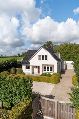 Op slechts 10 minuten van het centrum van Hasselt bevindt zich deze karaktervolle gezinswoning, waar tijdloze elegantie en hedendaags wooncomfort naadloos in elkaar overvloeien. De eigendom werd zeer grondig en met veel oog voor detail gerenoveerd, waarbij uitsluitend voor kwalitatieve materialen is gekozen. Vanaf de eerste aanblik overtuigt het huis door zijn verzorgde architectuur met een helder witgeschilderde gevel, een stijlvol donker dak en een prachtig aangelegde voortuin met strak vormgeknipte hagen. De robuuste houten voordeur geeft het pand een warme en residentiële uitstraling. <br /><br />Binnenin speelt een overvloedige natuurlijke lichtinval de hoofdrol, wat zorgt voor een uitgesproken ruimtelijk gevoel over de volledige woonbeleving van 200m². De inkomhal, voorzien van een vestiaire en gastentoilet, leidt naar een sfeervolle woonkamer. Aansluitend bevindt zich een hoogwaardige maatkeuken met een gezellige ontbijthoek. De strakke uitbreiding aan de achterzijde, afgewerkt met grote raampartijen, creëert een open en lichtrijk woonconcept met een optimaal contact met de buitenruimte. Verder biedt het gelijkvloers de luxe van een eigen masterbedroom met een aangrenzende ensuite badkamer, wat levenslang en comfortabel wonen garandeert. <br /><br />De eerste verdieping werd specifiek doordacht voor het gezinsleven en herbergt drie volwaardige slaapkamers, samen met een tweede badkamer die volledig is ingericht op maat van kinderen. Verder is de woning deels onderkelderd, wat bijzonder praktisch is met de aanwezigheid van een wasruimte, de centrale verwarming en extra opbergruimte. Dat het huis met visie is gerenoveerd, vertaalt zich eveneens in een zeer gunstig energielabel B.<br /><br />Rondom het huis ligt een schitterende tuin, met zorg ontworpen door een landschapsarchitect om maximale privacy en rust te garanderen. Het brede gazon en het uitgebalanceerde groen vormen een perfect decor om te ontspannen. Er zijn diverse mooie leefterrassen aangelegd, waaronder een ruim overdekt terras dat direct aansluit op de woning, alsook een sfeervolle plek onder de boom. Het perceel wordt vervolledigd door een riante vrijstaande garage met plaats voor twee wagens en een praktische achterliggende tuinberging. Dit is een woning voor wie op zoek is naar een instapklare, luxueus afgewerkte thuis op een uitstekende locatie.