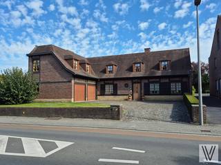 Centraal gelegen ruime verzorgde villa op 737 m², bestaande uit de inkomhal met toilet, (slaap)kamer/polyvalente ruimte,  woon/leefruimte (alle met inbouwspots) met aansluitend de nieuwe keuken, zonnige veranda, berging/wasruimte en 2de toilet, dubbele garage, tuin met terras en bijgebouw met sauna en douche.. Op het verdiep zijn er maar liefst 5 slaapkamers telkens met inbouwkasten en lavabo. Zolder. Houten ramen met dubbel glas. De woning is ingericht met kwalitatieve materialen. Open haard. Kelder. Zonnepanelen. Er is plaats voor 4 auto's op de oprit.