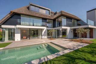 Magnifieke alleenstaande nieuwbouwvilla, hoogwaardige afgewerkt, in een rustige residentiële villawijk met perfecte zonoriëntatie. Prachtig zuidergericht perceel voorzien van een zwembad. Indeling: royale inkomhal met ingemaakte vestiairekasten en gastentoilet. Lift van de -1 tot +1. Door de grote raampartijen genieten de leefruimtes van een natuurlijke lichtinval en bieden ze een prachtig zicht op de tuin met zwembad. De gezellige leefruimte is voorzien van een sfeervolle gashaard, aansluitend een aparte bureauruimte met ingemaakte kasten. De ruime leefkeuken met eetplaats, eveneens uitgerust met gashaard is voorzien kwalitatieve toestellen van Miele (wijnkoeler, oven, combi oven micro-oven, vaatwasser, Amerikaanse frigo/diepvries Liebherr). Via de grote schuiframen heeft men toegang tot een overdekt terras met BBQ. Aansluitend een praktische bijkeuken met wasruimte. Eerste verdieping: nachthal met berging, 3 volwaardige slaapkamers, die elk voorzien zijn van een dressing en ensuite badkamer (lavabo, douche, toilet en bad) die zeer luxueus afgewerkt zijn. Tweede verdiep: vierde en vijfde slaapkamer met ingemaakte kasten en een douchekamer. Extra bergruimte. Garage voor twee wagens en een golfcar. Buitenparking. Kelder met verschillende ruimtes oa. technische ruimte, wijnkelder mogelijk, berging, ... Architect Luc De Beir, binnenhuisarchitect Brian Chielens, tuin door Dominik Eeman. Automatische besproeiing, tuinverlichting, camera, Vola kraanwerk, zwembad (warmtepomp), lift, geothermie. Verkoop onder registratierechten. Contacteer Knokke Real Estate om een bezoek in te plannen.