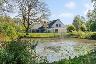 Charmante villa met ruime uitbreidingsmogelijkheden op een uniek privé-domein grenzend aan natuurgebied te Schilde<br /><br />In één van de meest gegeerde en residentiële buurten van Schilde, discreet gelegen aan het einde van een doodlopende straat, bevindt zich deze karaktervolle villa op een uitzonderlijk perceel van ca. 14.990 m², waarvan een deel ingericht werd voor het houden van dieren met eigen verblijf. Een locatie waar rust, privacy, natuurbeleving en comfort naadloos samenkomen.<br /><br />Indeling gelijkvloers:<br />De villa verwelkomt u via een ruime en lichtrijke inkomhal met vestiaire en gastentoilet. Vanuit hier bereikt u de aangename leefruimte met open haard en grote raampartijen, die zorgen voor een prachtig uitzicht op de fraai aangelegde tuin. Aansluitend bevindt zich een sfeervolle leefveranda, volledig omringd door schuiframen en voorzien van automatische zonnescreens, zodat u het hele jaar door geniet van een maximale lichtinval en een harmonieus zicht op het groen.<br /><br />De volledig uitgeruste keuken biedt eveneens zicht op en directe toegang tot het terras en wordt vergezeld door een praktische berging. Aansluitend bevindt zich een tweede gezellige leef- en eetruimte, voorzien van een houtkachel, wat deze ruimte bijzonder warm en uitnodigend maakt. Tevens is er een aparte bureauruimte, ideaal voor wie praktijk- of kantooractiviteiten aan huis wenst. De inpandige garage met automatische poort biedt plaats aan twee voertuigen.<br /><br />Eerste verdieping:<br />De nachthal leidt naar de master bedroom met ensuite badkamer, aangevuld met drie comfortabele, volwaardige slaapkamers. Daarnaast is er een tweede badkamer met douche en een bijzonder ruime, functionele wasplaats.<br /><br />Tuin en buitenbeleving:<br />De zuidwest-georiënteerde parktuin vormt een ware oase van rust, met weidse vergezichten en een bijzonder harmonieuze groenbeleving. De tuin werd smaakvol aangelegd, inclusief een fraaie vijverpartij, en beschikt bovendien over een bijgebouw/stal voor het houden van dieren — ideaal voor paarden- of dierenliefhebbers, of voor wie een hobbyproject wenst te realiseren.<br /><br />Bijzonderheden:<br />- Maximale privacy, prestigieuze ligging &amp; ideale zonoriëntatie<br />- Renovaties: 1997 (aanbouw leefruimte) – 1999 (gedeeltelijk buitenschrijnwerk)<br />- Verwarming op aardgas (Viessmann) via radiatoren en convectoren<br />- Dubbele beglazing (hout &amp; aluminium)<br />- Rolluiken aanwezig<br />- Videofonie &amp; automatische toegangspoort<br />- Oprit met plaats voor ca. 6 wagens<br />- Bergzolder toegankelijk via vlizotrap