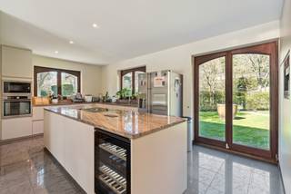 In a quiet and green environment in Schoten, you will find this spacious Spanish villa on a generous plot of 8,670 m². This property combines characterful architecture with functionality and numerous possibilities, both private and professional, thanks to the presence of a separate building.<br /><br />We can easily park our cars on our own property and have a wide choice; in one of the many open parking spaces, under the carport, or in the garage.<br /><br />Through the spacious entrance hall, you enter the bright living room, equipped with a cozy wood fireplace and a built-in bar - perfect for enjoyable evenings. Adjacent is a spacious and stylish office with built-in cabinets, ideal as a home office.<br /><br />The kitchen is fully equipped and features a kitchen island and a spacious breakfast area that offers a beautiful view of the beautifully landscaped garden and the inviting swimming pool. Adjacent is a spacious utility room.<br /><br />On the other side of the house, there are three full bedrooms and two bathrooms. Two bedrooms share a modern bathroom with shower, sink, and toilet. The master bedroom has its own dressing room and an ensuite bathroom with a whirlpool bath, double sink, and toilet - a true private oasis.<br /><br />Furthermore, on the ground floor, there is a laundry room, an indoor garage, while outside a carport is provided for three cars and plenty of open parking spaces.<br /><br />In addition to the ground floor living, the villa also houses a finished first floor which is furnished as a studio. This separate studio has its own living room, bedroom, and bathroom - ideal for guests, an au pair, or as an additional living unit.<br /><br />In the garden, two spacious outbuildings are located. One of them is furnished as a massage practice consisting of a ground floor area and a fully equipped basement. The other outbuilding has a double layout; one part as a storage and garage, and another part is furnished as a yoga and relaxation area. This building is also accessible via a separate entrance, ensuring optimal separation of the private and professional areas. Both buildings are perfectly adaptable to personal or professional needs.<br /><br />Finally, the property offers a covered terrace, a spacious swimming pool, and solar panels, and is completely fenced.<br /><br />A unique property that effortlessly combines space, privacy, and versatility in one of the most beautiful neighborhoods in Schoten.<br /><br />Extraordinary features<br />- Green environment<br />- Privacy<br />- Spacious villa and outbuildings<br />- Live-work combination<br />- Lots of natural light<br />- Pleasant surroundings<br />- Very spacious plot with two access options: private and business.