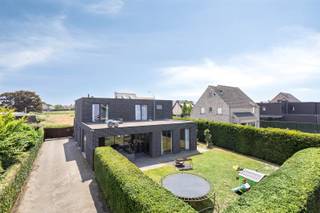 OPEN HUIS ZATERDAG 20 DECEMBER van 14u tot 16u - Graag inschrijven. Bent u op zoek naar een unieke combinatie van een ruime recente woning, kangoeroewoonst / co-housing en een geweldig groot bijgebouw?. Hier heb je werkelijk zoveel mogelijkheden: ideaal voor zij die enorm veel opslagruimte / plaats voor voertuigen nodig hebben, of voor een atelier / welness-/fitnessruimte(s), ouders en kinderen / familie die samen wonen en toch apart, verzamelaars, zoveel mogelijkheden! De hoofdwoning is een moderne woning met loftlook / industriële look en heeft een bewoonbare oppervlakte van 335 m², en omvat o.a. 4 slaapkamers, waarvan 2 met dressing en badkamer, zeer ruime en lichte woonkamer van ca 70 m² en aansluitend een grote, volledig ingerichte luxe open keuken (stoomoven, combi-magnetron, oven met grill, wijnkast, Quooker, Espressomachine, koel-vriescombinatie, vaatwasser, inductiekookplaat), wasplaats , gastentoilet en groot bureel vooraan. Het bijgebouw bestaat uit een genre instapklare kangoeroewoonst en aansluitend vinden we de zeer grote geïsoleerde hal die dienst kan doen als opslagruimte en of / fitness / wellness / atelier etc. Momenteel is er een fitnessruimte, een schoonheidskamer en een zoutkamer in ondergebracht. Er zijn 4 poorten in de hal (1 van 3 meter hoog en 3 van 2,25 m hoog). Ideaal ook voor heftruck, bestelwagen... Er zijn ruimtes van bij benadering 172 m², 100 m², 135 m², 85 m² en 73 m². Verder nog wat kleinere ruimten. Er is ook een toilet voorzien voor het bijgebouw en er is een aansluiting om een douche te plaatsen. Het 'bijhuisje' ('kangoeroewoonst') is instapklaar: alles wat je nodig hebt is er: ingerichte keuken, badkamer, slaapkamer, wasplaats / berging. Niet gelegen in een overstromingsgebied . P-score: B - G-score: A.Overname bepaalde meubels is ook bespreekbaar. Gunstige centrale ligging, nabij de dorpskern, scholen...Als er nog voor 10000 Wpiek zonnepalen bijkomen komt de EPC-waarde op 64 KWh/m²jaar.