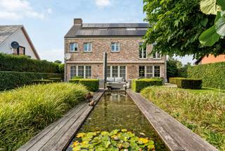 Prachtige villa met 6 slaapkamers op een mooi perceel van 1.329 m². Op het gelijkvloers ruime leefruimte met eetkamer, salon, ingerichte keuken met ontbijthoek, wasplaats en dubbele inpandige garage. Op de eerste verdieping bevinden zich 3 slaapkamers, badkamer, dressing en apart toilet en via een aparte trap nog een logeerkamer met ensuite douchekamer. Op de zolderverdieping bevinden zich nog 2 extra slaapkamers en de CV-ruimte.<br /><br />Mooie, diepe tuin met prachtig zonneterras, siervijver en tuinhuis.<br /><br />Indeling gelijkvloers:<br />Via de ruime inkomhal met gastentoilet heeft u onmiddellijk toegang het woongedeelte. Deze is zeer ruim opgevat en bestaat uit een lichte eetkamer met prachtig zicht over de tuin en een gezellige zitkamer met inbouwcassaette (op gas). Vanuit alle leefruimten heeft u een prachtig zicht op de aangelegde tuin met siervijver achteraan.<br />Aansluitend aan de eetkamer bereiken we de luxe leefkeuken voorzien van een gaskookplaat (6 pits), heteluchtoven, microgolfoven, stoomoven, vaatwasser en Amerikaanse koelkast (overname in overleg). <br />Tevens is er een ruime en praktische bijkeuken/wasplaats en een dubbele inpandige garage.<br />Eerste verdieping:<br />Via een aparte trap in de bijkeuken komt u in een aparte logeerkamer met aansluitend douchekamer (douche, wastafel en toilet) boven de garage.<br />Via de trap in de inkomhal komt u op de 1ste verdieping en hier biedt de nachthal toegang tot 3 slaapkamers op deze verdieping. Deze zijn allen voorzien van op maat gemaakte kasten en de hoofdslaapkamer is voorzien van een ruime dressing. Verder is er nog een apart toilet en een volledig ingerichte badkamer (dubbele wastafel, douche en ligbad). <br />Tweede verdieping:<br />Via een vaste trap komen we tot dit volwaardige extra verdiep. Hier treffen we de Cv-ruimte en nog 2 extra slaapkamers, waarvan één voorzien van op maat gemaakte kasten.<br /><br />BIJZONDERHEDEN<br />- Alarmsysteem<br />- 20 zonnepanelen + batterij<br />- CV op aardgas<br />- Grondwaterput aanwezig (voor automatische beregening van de tuin – 5circuits)<br />- Zuidgerichte tuin