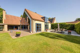 <p>Gelegen in een residentiële en groene woonomgeving bevindt deze villa zich op een royaal perceel van ca. 2.715 m², in een doodlopende straat. De fraai aangelegde tuin met vijverpartij geeft het geheel een aangenaam parkgevoel. Rust, ruimte en privacy zijn slechts enkele troeven van deze degelijke woning.<span></span></p>
<p>Bovendien is er weinig doorgaand verkeer, wat zorgt voor een veilige omgeving voor kinderen, wandelaars en fietsers. Het Zoerselbos, met ca. 400 hectare natuurgebied, bevindt zich op slechts 3 km afstand.</p>
<br /><span><strong>Indeling<br /><br /></strong></span>Inkomhal met gastentoilet voorzien van handenwasser, vestiaireruimte en toegang tot een polyvalente kamer van ca. 10 à 12 m², momenteel ingericht als hobbykamer. Verder bereikt u de leefruimte, die gekenmerkt wordt door royale volumes en veel natuurlijke lichtinval. Deze omvat momenteel een bureau met open haard en zicht op de tuin, een ruime zithoek met plafondhoogte tot in de nok en voorzien van een houtkachel, een afzonderlijk tv-salon, een eetkamer en een volledig ingerichte keuken (2000).
<p>Vanuit de keuken is er toegang tot de inpandige garage met aparte wasplaats. Via de garage bereikt u tevens de droge, geklimatiseerde wijnkelder.</p>
<span><strong>Verdieping<br /><br /></strong></span>De verdieping beschikt over twee met elkaar verbonden overlopen. De eerste, bereikbaar vanuit de inkomhal, geeft toegang tot drie slaapkamers. De tweede overloop, die eveneens rechtstreeks vanuit de leefruimte bereikbaar is, leidt naar de ruime hoofdslaapkamer met een grote ingemaakte kastenwand.
<p>De twee overlopen vloeien in elkaar over, maar kunnen desgewenst van elkaar worden gescheiden door middel van een deur.<span></span></p>
<p>Daarnaast omvat deze verdieping een ruime berging met Velux-dakraam, een badkamer met dubbele lavabo, ligbad en douche, en een afzonderlijk nachttoilet.<br /><br />Het creëren van een tweede badkamer is relatief eenvoudig realiseerbaar.</p>
<br /><span><strong>Tuin<br /></strong></span><br />Volledig omheinde tuin met een afsluiting van ca. 1,80 m hoog. De tuin beschikt over een grote vijverpartij, twee terrassen en een boomgaard.<br /><br /><span><strong>Bijzonderheden</strong></span>
<ul>
<li>Bevloering in natuursteen en parket</li>
<li>Verwarming deels elektrisch (radiatoren en accumulatoren) en deels op aardgas (vloerverwarming)</li>
<li>Houten en aluminium ramen met dubbele beglazing</li>
<li>Droge, geklimatiseerde wijnkelder</li>
<li>Voorzieningen voor aansluiting op de riolering zijn reeds aanwezig</li>
<li>EPC: label D – 326 kWh/m² jaar - <span><strong>EPC label C </strong></span>na plaatsen zonnepanelen (simulatie)</li>
<li>EPC-certificaat: UC 3890393</li>
<li>Elektriciteit wordt conform opgeleverd</li>
</ul>
<p><span><strong><br />Stedenbouwkundige inlichtingen</strong></span><span></span></p>
<p>Vg – Wg – Gvv – Gvkr – Gmo – Gworg</p>
