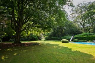 <p><span>Située dans le très prisé quartier de Kapellen-Bos, sur un magnifique terrain orienté sud-ouest d’environ 4.577 m², cette villa d’exception a été récemment rénovée avec un souci du détail remarquable et des matériaux haut de gamme. Elle allie avec élégance le charme intemporel au confort contemporain et bénéficie d’un environnement verdoyant offrant une intimité absolue.</span></p>
<p><span>Dès l’entrée, vous êtes accueilli dans un hall spacieux avec vestiaire et toilettes invités. De superbes portes vitrées en acier mènent à un élégant salon cocktail équipé de meubles sur mesure, qui s’ouvre harmonieusement sur un vaste espace de vie baigné de lumière, agrémenté d’un feu ouvert ainsi que d’un confortable salon et coin télévision. L’espace bureau surélevé constitue une zone de vie supplémentaire offrant de nombreuses possibilités d’aménagement.</span></p>
<p><span>Le cœur de la maison est sans conteste la cuisine familiale luxueusement équipée avec son grand îlot central, ses appareils de qualité supérieure et sa superbe orangerie accueillant la salle à manger. Les larges baies vitrées offrent depuis chaque pièce de vie une vue imprenable sur le jardin paysager et la nature environnante. Une arrière-cuisine entièrement aménagée avec de nombreux espaces de rangement complète cet ensemble. La propriété dispose également d’un double garage intégré.</span></p>
<p><span>À l’étage, la villa propose trois chambres spacieuses. La suite parentale bénéficie de placards intégrés, d’un dressing et d’une élégante salle de bains privative équipée d’une double douche à effet pluie et d’une double vasque. Les deux autres chambres se partagent une seconde salle de bains avec baignoire. Un WC séparé est également présent à cet étage. Un escalier escamotable permet d’accéder à un vaste grenier de rangement occupant toute la largeur de la maison.</span></p>
<p><span>À l’extérieur, vous profiterez d’un magnifique jardin paysager agrémenté d’arbres matures, de plusieurs terrasses ensoleillées ainsi que d’une piscine chauffée avec pompe à chaleur et solar deck. Une élégante dépendance en chêne abrite un carport pour trois véhicules, un local de rangement pour le jardin ainsi que les installations techniques de la piscine. La vaste allée pavée, le double garage intégré et le carport offrent de nombreuses possibilités de stationnement.</span></p>
<p><span>Cette villa prête à emménager se distingue non seulement par son niveau de finition exceptionnel et son caractère unique, mais également par la présence de 24 panneaux solaires avec certificats verts.</span></p>
<p><span>Une propriété exclusive où luxe, confort et sérénité se conjuguent à la perfection.</span></p>