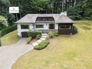 Ontdek deze unieke eigendom in Maarkedal, waar elegantie en natuurlijke schoonheid naadloos samenkomen. Met een indrukwekkende bewoonbare oppervlakte van 453 m², midden in een bosrijk landschap en omringd door weelderig groen, biedt deze woning een oase van rust en verfijning.Bij binnenkomst verwelkomt een ruime inkomhal u en leidt u naar een lichtrijke woonkamer, ideaal voor gezellige avonden met familie en vrienden. De stijlvolle eetkamer sluit aan op een te moderniseren keuken die direct toegang geeft tot een zonneterras. Hier beleeft u ontspannen diners in openlucht, omgeven door stilte en groen.De woning beschikt over vijf slaapkamers en twee badkamers, waardoor er voldoende ruimte is voor een groot gezin of logees. Het interieur ademt nostalgie en warmte, verrijkt met vintage accenten die zorgen voor een tijdloze uitstraling.Verder ontdekt u een royale kelderverdieping met wijnkelder. De dubbele garage biedt niet alleen plaats voor meerdere voertuigen, maar is ook dienstig voor praktische bergruimte.Ook buiten is dit eigendom een parel: de tuin garandeert privacy en vormt een waar paradijs voor natuurliefhebbers. Deze woning combineert rust, ruimte en authenticiteit met talloze mogelijkheden voor persoonlijke invulling. Een zeldzame kans om een stukje paradijs in het hart van de natuur uw thuis te noemen.