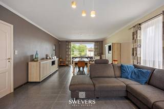 Voor meer info en foto’s, surf naar www.swevers.be – Deze ruime open bebouwing aan de Proenhofstraat 28 in Tongeren combineert een rustige, landelijke ligging met veel woonruimte en een groen uitzicht. De woning werd gebouwd in 1993, biedt 205 m² bewoonbare oppervlakte en staat op een royaal perceel van 11a 55ca. Op het gelijkvloers vind je een centrale inkomhal, een ruime woonkamer van 35,94 m² en een grote leefkeuken van 31,07 m², vernieuwd in 2015. Verder zijn er een praktische wasplaats/berging, een bureau en een afzonderlijk toilet. De eerste verdieping telt vier volwaardige slaapkamers van 14,45 m² tot 20,94 m². De badkamer, vernieuwd in 2010, beschikt over een ligbad, douche, wastafel en toilet. Een belangrijke extra troef is de volledig onderkelderde verdieping van maar liefst 105,62 m², ideaal voor stockage, hobby’s en andere praktische toepassingen. Daarnaast is er een garage van 24 m². Buiten geniet je van een noordoostelijk georiënteerde tuin, een overdekt terras en een groene, open omgeving. De tuin en oprit werden in 2019 vernieuwd. School en openbaar vervoer bevinden zich vlakbij, terwijl het centrum van Tongeren op circa 4 km ligt. Een instapklare gezinswoning met vier slaapkamers, bijzonder veel bergruimte en een rustige ligging. Voor meer informatie, bel 011 255 155. Bron bewoonbare oppervlakte: EPC – verslag.