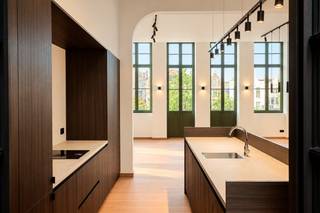 TREVI GENT: Luxe 2 slaapkamer appartement<br />Betreed een wereld van ongeëvenaarde luxe, gelegen in het kloppende hart van Gent, pal op de Vrijdagmarkt. Deze weelderige eerste verdieping van het historische 'Tooghuis' brengt tijdloze charme en moderne verfijning harmonieus samen. Stap in de lift die uitkomt in de riante woonkamer met een indrukwekkende plafondhoogte van maar liefst 3,80 meter. De prachtige houten vloer straalt warmte uit, terwijl het balkon u trakteert op een spectaculair uitzicht op het standbeeld van Jacob van Artevelde. De hypermoderne open keuken, compleet met hoogwaardige inbouwapparatuur en stijlvolle kasten, ademt pure klasse. Direct naast de keuken vindt u een afgesloten terras, perfect voor ongestoord genot. Achterin de woning wacht een luxueuze badkamer met inloopdouche op u, ontworpen om u te verwennen. Vervolgens zijn er de twee comfortabele slaapkamers. Vergeet niet de vloerverwarming en warmtepomp voor optimaal comfort. Dit exclusieve pand belooft niet alleen een ongeëvenaarde levensstijl, maar ook de unieke kans om deel uit te maken van de rijke geschiedenis en cultuur van Gent. Mis deze zeldzame gelegenheid niet om in alle luxe en comfort te wonen, omringd door de levendige sfeer van de Vrijdagmarkt. <br />Beschikbaar op 1 november<br />€1850 + €100 syndicale kosten