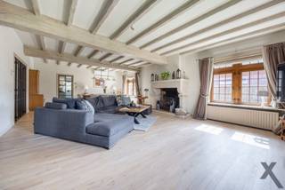 In de residentiële wijk ‘Den Drijhoek’ te Schilde, een buurt die bekendstaat om haar rustige en groene karakter bevindt zich deze indrukwekkende villa op een royaal perceel. Bij het betreden van de woning via de elegante inkomhal met gastentoilet, wordt u direct omarmd door een sfeer van tijdloze klasse. De royale L-vormige leefruimte ademt karakter dankzij de massieve parketvloer, authentieke balkenpartijen en sfeervolle haarden.
Aansluitend vindt u de droom van elke culinaire liefhebber: een hyper-uitgeruste keuken waar enkel genoegen is genomen met het beste. Terwijl de knalrode elektrische AGA de show steelt, zorgen de Sub-Zero koel-vriescombinatie en het keukeneiland met wijnkoeler en professionele wokplaat voor een gastronomische ervaring op topniveau.
Het doordachte ontwerp biedt u het comfort van een grote slaapkamer op het gelijkvloers met aparte toegang van buiten. Vanuit deze slaapkamer ontwaakt u met een rustgevend uitzicht op de tuin en het zwembad, terwijl de dressing met maatwerk en de en-suite badkamer met inloopdouche een gevoel van hotelsuite-luxe geven.
Op de verdieping leidt een riante overloop naar een master suite met en-suite badkamer en nog 3 royale slaapkamers. Een derde badkamer en een separate wasplaats vervolledigen dit niveau.
Buiten transformeert het perceel in een private oase. Het verwarmde zwembad wordt omringd door zonneterrassen, overdekte terrassen en een sfeervolle patio met buitenhaard, de ideale plek voor lange zomeravonden. Deze villa is technisch klaar voor de toekomst met zonnepanelen, airco, camerabewaking, een oplaadpunt voor elektrische wagens en tuinberegening. Een dubbele garage en een koele wijnkelder maken dit unieke plaatje compleet. Een residentie waar luxe, veiligheid en leefplezier elkaar ontmoeten. Plan vandaag nog uw bezoek in en laat u betoveren door deze prachtige woning.