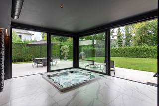 <p><strong>Exclusieve villa te koop in het prestigieuze domein van Bouchout – Wemmel</strong></p>
<p><strong>Een unieke combinatie van luxe, comfort en locatie</strong></p>
<p>In het hart van het gegeerde domein van Bouchout te Wemmel, stellen wij u met trots deze uitzonderlijke villa voor. Deze stijlvolle woning werd volledig gerenoveerd in 2023 en straalt klasse en sereniteit uit, en biedt alles wat u verwacht van een eigendom op toplocatie.</p>
<p><strong>Indeling & Comfort</strong></p>
<p>Bij het betreden van de woning komt u in een ruime inkomhal met vestiaire en gastentoilet – een warm welkom voor u en uw gasten. De leefruimtes zijn ontworpen met oog voor detail en comfort: een super geïnstalleerde keuken met kwalitatieve apparatuur vormt het hart van de woning, naadloos verbonden met een lichtrijke eetkamer en een ruim, gezellig salon met open haard en indrukwekkende vide.</p>
<p>Daarnaast is er een aparte bureauruimte die perfect kan dienen als vierde slaapkamer of polyvalente ruimte.</p>
<p><strong>Slaapcomfort & Privacy</strong></p>
<p>De woning beschikt over <strong>drie volwaardige slaapkamers</strong>, elk met een eigen <strong>en-suite badkamer</strong>. Eén van de slaapkamers geniet bovendien van een <strong>privéterras</strong>, ideaal om in alle rust van de ochtendzon te genieten.</p>
<p><strong>Perfect voor vrije beroepen of zelfstandigen</strong></p>
<p>Een absolute meerwaarde is de aparte ruimte met eigen ingang, momenteel ingericht als <strong>beautysalon</strong>. Deze kan perfect dienst doen als <strong>home office</strong>, praktijkruimte of voor een ander vrij beroep, volledig afgescheiden van het privégedeelte van de woning.</p>
<p><strong>Exclusieve wellness aan huis</strong></p>
<p>Pure verwennerij: aansluitend aan het salon bevindt zich een volledig <strong>inpandige wellnessruimte</strong>, uitgerust met een <strong>sauna</strong>, <strong>jacuzzi</strong>, <strong>douchekamer</strong> en extra <strong>WC</strong>. Via grote schuiframen geniet u van een vlotte toegang tot de <strong>zuidgerichte tuin</strong>, met prachtig aangelegd terras – een oase van rust en privacy.<br /><br /><strong>Extra troeven</strong><br /><br />Naast het comfort dat deze villa biedt zijn er nog leuke extra's: alarminstallatie met camerabewaking, airco, zonnepanelen, waterverzachter, twee elektrische laadpalen, 4 buitenstaanplaatsen, ...</p>
<p><strong>Uw nieuwe thuis of professionele uitvalsbasis?</strong></p>
<p>Deze eigendom is een zeldzame kans voor wie wonen en werken op hoog niveau wil combineren, op een topligging in de rand rond Brussel.</p>
<p>Contacteer ons vandaag nog voor een exclusieve rondleiding en laat u verleiden door de luxe en mogelijkheden van deze prachtige villa in Wemmel.</p>
<p></p>
<p></p>
