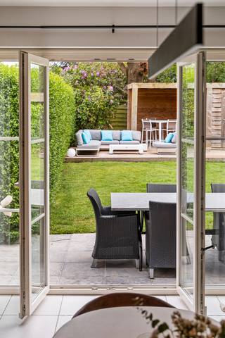 Locatie
Deze halfopen bebouwing is gelegen in Hove, langs de Mechelsesteenweg. Ondanks de centrale ligging geniet u in de woning en de tuin van een aangename rust. Dankzij de onmiddellijke nabijheid van belangrijke invalswegen en de vlotte verbinding richting Mortsel, is dit de ideale uitvalsbasis voor wie comfortabel en centraal wil wonen.
Indeling
De woning, gebouwd in 2007, beschikt over een inkomhal met gastentoilet. De lichtrijke leefruimte met eetplaats en open keuken vormt het hart van de woning en creëert een aangenaam gevoel van ruimte en verbondenheid. Via de eetkamer heeft u directe toegang tot de zonnige tuin met twee terrassen, ideaal om op elk moment van de dag van de zon te genieten. Aansluitend zorgen de praktische bijkeuken en de ruime garage voor extra comfort en bergruimte.
Op de eerste verdieping bevindt zich de ruime masterbedroom van ca. 20 m² met dressing en een badkamer uitgerust met zowel bad als douche. Daarnaast is er een tweede kamer die perfect kan dienen als slaapkamer, bureau of hobbyruimte.
De tweede verdieping biedt een ruime oppervlakte van ca. 40 m² en is momenteel ingericht als extra slaapkamer met bureauruimte. Deze verdieping beschikt bovendien over een tweede badkamer met douche.
Troeven
- Energiezuinig (EPC-label A)
- Zonnepanelen
- 3 volwaardige slaapkamers
- Ruime garage
- Zonnige tuin
- Gegeerde buurt
Technische gegevens
De woning blinkt uit in energiezuinigheid en wooncomfort. Dankzij de aanwezige zonnepanelen en de recente gasketel geniet u van een laag energieverbruik. Dit vertaalt zich in een uitstekend EPC-label A, wat een sterke meerwaarde biedt naar de toekomst toe. Bovendien is de elektriciteit volledig conform.