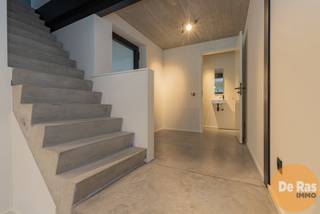 VLIERZELE - Deze recente nieuwbouwwoning combineert een strakke betonarchitectuur met een warme, moderne uitstraling en een bijzonder energiezuinig karakter (E-peil 4). Vooraan de woning bevinden zich een praktische carport en een aparte fietsenberging, wat zorgt voor extra comfort in het dagelijks gebruik.<br /><br />Via de inkomhal met gastentoilet kom je in de open leefruimte, waar de zithoek en keuken mooi in elkaar overlopen. De grote raampartijen zorgen voor veel natuurlijk licht en bieden een aangenaam zicht op de zuidgerichte tuin. Dankzij het geïntegreerde domoticasysteem geniet je bovendien van extra gebruiksgemak.<br /><br />Op de eerste verdieping is er een ruime nachthal die perfect kan dienen als bureau, hobbyruimte of extra zithoek. Verder vind je hier twee volwaardige slaapkamers, een apart toilet en een moderne badkamer.<br /><br />De vaste trap leidt naar de volledig afgewerkte zolderverdieping, die flexibel kan ingericht worden als extra slaapkamer, werkruimte of ontspanningsruimte.<br /><br />Een ideale woning voor wie op zoek is naar hedendaags wooncomfort, energiezuinigheid en een doordachte indeling.<br /><br />Kortom bent u op zoek naar stevige goed onderhouden woning met een ruime bewoonbare oppervlakte, voorzien van 4 slaapkamers, garage en grote tuin met heel wat mogelijkheden, aarzel dan niet en maak snel uw afspraak!! Voor meer info of bezoek 053/60.65.60