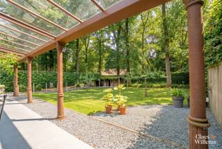 In het gegeerde Bois du Strihoux in Rebecq bevindt zich deze verzorgde villa op een perceel van 12 are 36 centiare. De ligging is bijzonder: het Bois du Strihoux maakt deel uit van het historische boscomplex Bos Ter Rijst – Bois du Strihoux, dat ooit ongeveer 360 hectare omvatte. Vandaag vormt deze groene residentiële omgeving een van de meest gewaardeerde woonzones van Waals-Brabant, met brede dreven, grote percelen, privacy en een rustige sfeer. Hier woont u midden in het groen, terwijl Halle, Tubeke, Edingen en Brussel vlot bereikbaar blijven.
Via de automatische toegangspoort bereikt u het afgesloten perceel. De tuin met volwassen bomen biedt zithoeken waar u in alle rust geniet van de groene omgeving. De verwarmde dual-zone swimspa met tegenstroominstallatie en de ruime jacuzzi vormen samen een exclusieve privéwellness. Dankzij de doordachte verwarmingsinstallatie blijven de gebruikskosten beperkt: het zwemgedeelte benut de energie van de zonnepanelen, terwijl het jacuzzigedeelte via een warmtewisselaar op de centrale verwarming wordt verwarmd.
Op het gelijkvloers bevinden zich de leefruimte met open haard, de eetplaats en de open keuken. Dankzij de schuifdeur kan het afzonderlijke salon worden afgesloten en ingericht als bureau, leeskamer of extra zithoek.
De eerste verdieping omvat drie ruime slaapkamers. Twee slaapkamers worden verbonden door een tussenliggende badkamer. Daarnaast is er een afzonderlijke douchekamer met toilet.
Ook de kelderverdieping biedt veel mogelijkheden. Hier bevindt zich een ruime homecinema of tv-zaal met grote raampartij en daglicht. De ruimte is voorbereid voor 5.1 surroundgeluid. Verder beschikt deze verdieping over een extra douchekamer en een ruimte voor hobby, fitness, speelkamer of praktijkruimte.
Met een bruto vloeroppervlakte van 276 m² combineert deze villa ruimte, comfort en energiezuinigheid. De 27 zonnepanelen van samen 11,1 kWp, de regenwaterput van 10.000 liter, het bekabelde datanetwerk met wifi-access points, de voorbereiding voor een 22 kW-laadpaal, vernieuwde sanitaire leidingen, de grotendeels vernieuwde elektrische installatie en energiezuinige radiatoren maken deze woning klaar voor de toekomst.
De ligging in het Bois du Strihoux, de verwarmde swimspa, de jacuzzi, de ruime leefruimtes, de technische uitrusting en het groene perceel maken van deze villa te koop in Rebecq een zeldzame opportuniteit voor wie rust, privacy, natuur, wellness en modern wooncomfort wil combineren.