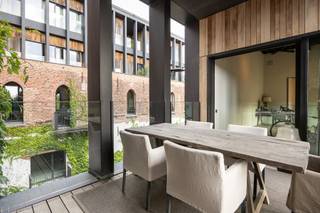 Op de historische Kanaalsite in Wijnegem, een voormalige graanstokerij uit 1857 langs het Albertkanaal, bevindt zich deze buitengewone penthouse van circa 330 m², eigenhandig ingericht door Axel Vervoordt.<br /><br /><span>Indeling:</span><br />De imposante leefruimte heeft een plafondhoogte van maar liefst 6,16m, gedragen door authentieke zwarte stalen kolommen en balken en met karakteristieke rondboogramen. De authentieke, verweerde muren en de strakke gietvloer benadrukken het industriële karakter en versterken het zeer openlijk ruimtegevoel.<br /><br />Onder de mezzanine bevindt zich de stijlvolle leefkeuken met bijkeuken. De keuken is uitgerust met donker houten maatwerkkasten met ingebouwde koffiecorner, een robuust kookeiland en een La Cornue-fornuis. De Vola-armaturen en de authentieke wandtegels versterken de tijdloze, pure uitstraling. <br /><br />Deze loft telt drie ruime slaapkamers, verdeeld over de eerste verdieping (één slaapkamer) en de tweede verdieping (twee slaapkamers). <br /><br />Blikvanger is de master bedroom op de vide, met een indrukwekkend uitzicht op de leefruimte. Deze master bedroom is uitgerust met een royale dressing, een en-suite badkamer en is ook gemakkelijk bereikbaar via de lift.<br /><br />De tweede slaapkamer dient momenteel als fitnessruimte en beschikt over een badkamer met douche. Eveneens rechtstreekse toegang tot het terras.<br /><br />De derde slaapkamer bevindt zich op het gelijkvloers, samen met de derde badkamer, met ligbad en dubbele wastafel.<br /><br />Ruim overdekt terras met open zicht.<br /><br />Inclusief 3 staanplaatsen en berging.<br /><br /><span>Bijzonderheden:</span><br />Gebruik van duurzame en hoogwaardige materialen - vloerverwarming op aardgas, domotica , stalen ramen, hoogrendementsglas, ventilatiesysteem, hoge plafonds en binnendeuren, gepolierde betonvloer, videofoon <br />Gemeenschappelijke kosten ca. 400 euro per maand (blokpolis, syndicus, onderhoud gemene delen, tuinonderhoud met snoeiplan) <br /><br />EPC label B - 166 kWh/m² - UC 2555207 - elektr. conform<br /><br />Vg-Wg-Gvv-Gvkr-Gmo-Gworg