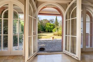 <p>Aan de rand van Hoogstraten bevindt zich deze statige villa, op wandelafstand van het centrum, winkels en horecazaken. De woning combineert royale ruimtes en karaktervolle elementen met een prachtig zicht op de groene tuin, waar u in alle rust en privacy kunt genieten.</p>
<p>Via de ruime inkomhal met gastentoilet en vestiaire komt u in de imposante traphal. Verder vindt u hier een bureel met ingemaakte kasten en een sfeervolle woonkamer met open haard. Grote raampartijen bieden een aangenaam uitzicht op de tuin. Ook de leefkeuken kijkt uit op het groen en is uitgerust met een Aga-fornuis en tal van ingemaakte kasten. Aansluitend bevinden zich een praktische bijkeuken met wasplaats en een extra vestiaire, met rechtstreekse toegang tot de tuin. In het bijgebouw bevindt zich bovendien een ruimte voor huishoudelijke apparaten, bereikbaar via een tussenruimte. De garage biedt plaats aan twee wagens achter elkaar. Via een vlizotrap bereikt u vanuit de garage de zolder.</p>
<p>Op de eerste verdieping bevinden zich vijf ruime slaapkamers en één kleinere kamer, evenals een badkamer. De kleinere kamer biedt de mogelijkheid om een tweede badkamer in te richten. Een vaste trap leidt naar de zeer ruime zolder, die gedeeltelijk geïsoleerd is.</p>
<p>De woning beschikt over ruime kelders met een goede plafondhoogte, waaronder een provisiekelder, wijnkelder en stookkelder met mazoutverwarming. Achteraan strekt zich een diepe, westelijk georiënteerde tuin uit, met prachtige bomen en veel privacy. Dankzij de volwassen beplanting geniet u hier in alle rust, zonder inkijk van de buren.</p>
<p>Een karaktervolle villa met veel ruimte, praktische aanhorigheden en een uitzonderlijke tuin, op een bijzonder gunstige locatie nabij het centrum van Hoogstraten.</p>
<p>De woning is gelegen aan de Lodewijk De Konincklaan in Hoogstraten, op een gunstige locatie vlak bij het centrum. De levendige winkelstraat De Vrijheid, met haar gevarieerd aanbod aan winkels, speciaalzaken en horeca, bevindt zich op korte afstand. VisitHoogstraten</p>
<p>Ook op het vlak van bereikbaarheid is de ligging bijzonder praktisch. Hoogstraten heeft een vlotte aansluiting richting de E19 Antwerpen–Breda, terwijl station Noorderkempen in Brecht en verschillende busverbindingen bijkomende mogelijkheden bieden voor het openbaar vervoer.</p>
