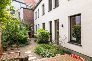 Dit unieke achterhuis is een zeldzame vondst: verborgen in alle rust, midden in de stad, volledig gerenoveerd en met een uitstraling waar Pinterest spontaan zenuwachtig van wordt.<br /><br />Vanop straat heb je geen idee wat zich achter de poort schuilhoudt. En dat maakt het net zo bijzonder. Achteraan het perceel ontdek je een verrassend rustige woonplek, volledig gerenoveerd in 2022 met een indrukwekkend gevoel voor stijl, warmte en slimme keuzes.<br />En het mooie? Het ziet er niet alleen goed uit, het zit ook technisch helemaal juist. Dankzij de grondige renovatie geniet je hier van een uitzonderlijk gunstig EPC A met E-peil E51, conforme elektriciteit, dakisolatie, vloerverwarming, airco en zonnescreens.<br />Een woning waar even hard aan comfort gedacht werd als aan esthetiek.<br /><br />Het gelijkvloers is zonder twijfel het pronkstuk van het huis. De leefruimte baadt in licht dankzij indrukwekkende ramen voor-en achteraan. De hoge plafonds, warme houten balken en stalen accenten zorgen voor een loftvibe. <br />De strakke zwarte keuken met royaal kookeiland op betonnen vloer vormt het kloppende hart van de woning. Een plek waar gasten automatisch blijven hangen “voor nog eentje” en waar elke zondagmorgen net iets trager mag verlopen.<br /><br />En dan de buitenruimtes, meervoud, want dit huis verwent je driemaal!<br />Het intieme koertje grenst direct aan de leefruimte: de plek voor je ochtendkoffie of gewoon even niets. Dan een verrassend groene tuin achteraan waar de stad plots héél ver weg lijkt, weelderig begroeid met klimplanten langs de oude bakstenen muren. En vooraan nog een extra terras waar stad en rust elkaar subtiel ontmoeten.<br /><br />Op de eerste verdieping bevinden zich twee slaapkamers, een apart toilet en een badkamer waar wellnessgevoel en design perfect samenkomen. Een vrijstaand bad, ruime inloopdouche en dubbele lavabo maken van deze ruimte een plek waar “ik neem snel een douche” opvallend vaak eindigt in een uur verdwijnen van de wereld.<br />De tweede verdieping telt nog twee extra kamers, waaronder een prachtige master bedroom met handige lavabo en extra kastruimte.<br /><br />Ook praktisch scoort deze woning moeiteloos punten. Er is een handige kelder voor extra opslagruimte en via de gedeelde toegangspoort parkeer je superhandig je (bak)fietsen.<br /><br />Een woning als deze laat zich moeilijk in vakjes stoppen. Te warm om strak te zijn. Te stijlvol om gezelligheid te verliezen. En vooral: veel te bijzonder om onopgemerkt te blijven.<br /><br />Troeven: <br />– Volledig & stijlvol gerenoveerd achterhuis <br />– 4 kamers <br />– Uitzonderlijk veel lichtinval <br />– Spectaculaire open leefruimte met blootgelegde balken <br />– Designkeuken met kookeiland <br />– Luxueuze badkamer met vrijstaand bad & inloopdouche <br />– 3 buitenruimtes: Koertje, weelderige tuin en terras <br />– Rustig gelegen en toch in hartje 2060<br />- Vraagprijs is richtprijs<br /><br />Wg, Gvkr, Gvv, Gmo, geen overstrominsgevoelig gebied