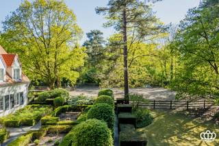 <p><span>Luxueuze villa opgetrokken in een tijdloze Knokkestijl, gelegen op een schitterende locatie: in een bosrijke, residentiële omgeving nabij het centrum van Heide en op wandelafstand van de Royal Antwerp Golf, op een oost gericht perceel van ca. 7.361 m², voorzien van o.a. 6 slaapkamers, 4 badkamers, paddock met stallen, mooi aangelegde vijver, prachtig aangelegde tuin en verwarmd zwembad met poolhouse. </span></p><p><span> </span></p><p><span>Gelijkvloers</span></p><p><span>Ruime inkomhal voorzien van een vestiaire en een gastentoilet met handenwasser. </span></p><p><span>Via een glazen deur betreedt u de royale, lichtrijke leefruimte op eiken parket, ingedeeld in een gezellige zithoek met sfeervolle houtkachel, een eetgedeelte en een orangerie op natuursteen. Vanuit de orangerie (voorzien van automatische zonnewering) geniet u van een idyllisch uitzicht op de aangelegde tuin en de aangrenzende paardenweide.</span></p><p><span>Aansluitend bevindt zich de leefkeuken uitgerust met een aanrecht in blauwe hardsteen voorzien van een Amerikaanse koelkast, vaatwasser en een kwalitatief 4-pits La Cornue-fornuis voorzien van: twee ovens (1 gas en 1 elektrisch), friteuse, teppanyaki-plaat en wokvuur. Ook hier is een aparte eethoek voorzien met zicht op de tuin.</span></p><p><span>De praktische bijkeuken/wasplaats beschikt over aansluitingen voor wasmachine en droogkast. Vanuit de bijkeuken is er toegang tot de ruime, dubbele inpandige garage met automatische poorten en ingemaakte kasten.</span></p><p><span>Verder is er, grenzend aan de inkomhal, een bureelruimte op eiken parket met ingemaakte kasten.</span></p><p><span> </span></p><p><span>Eerste</span><span> </span><span>verdieping</span></p><p><span>Via een open trap heeft u toegang tot de nachthal voorzien van ingemaakte kasten en de slaapkamers, allen op parket.</span></p><p><span>De masterslaapkamer is voorzien van een ensuite dressing en ensuite badkamer. Verder bevindt zich hier een beamer met uitrolbaar scherm en surround systeem én airco.</span></p><p><span>De tweede slaapkamer is uitgerust met een bureel en een ensuite badkamer. Daarnaast bevindt zich een derde slaapkamer met ingemaakte kasten. Verder is er een aparte fitnessruimte, die ook perfect dienst kan doen als vierde slaapkamer. Op deze verdieping bevindt zich nog een apart toilet en een aparte badkamer met stoomdouche. Vervolgens is er nog een vijfde slaapkamer.</span></p><p><span> </span></p><p><span>Zolder</span></p><p><span>Een vaste trap leidt naar een bijkomende zesde slaapkamer. Op deze verdieping bevindt zich ook nog een bergruimte en een extra kamer die naar wens ingericht kan worden.</span></p><p><span> </span></p><p><span>Kelder</span></p><p><span>Onder de villa is een droge kruipruimte aanwezig.</span></p><p><span> </span></p><p><span>Tuin</span></p><p><span>De villa is gelegen op een oost gericht perceel van ca. 7.361 m². Via een automatische houten poort met mooie oprijlaan heeft u toegang tot het perceel. Aan de voorzijde bevindt zich een mooi aangelegde tuin en een oprit die leidt naar de dubbele inpandige garage en carport.</span></p><p><span>Achteraan bevindt zich een verhoogd open terras, 2 vijvers waarvan 1 koivijver, een paddock of weide met paardenstallen en een verwarmde zadelkamer. tuin en paddock volledige gedraineerd, verlicht en eigen watervoorziening.</span></p><p><span>Verder is er een verwarmd zwembad met een volledig uitgerust poolhouse, voorzien van een overdekt terras, panorama sauna, bar, sanitaire voorzieningen, zithoek, muziekinstallatie, technische ruimte en een bergzolder. De tuin is voorzien van een automatisch beregeningssysteem. </span></p><p><span> </span></p><p><span>Bijzonderheden</span></p><p><span>- Gelegen op een gegeerde locatie: in een bosrijke, residentiële omgeving, nabij het centrum van Heide en op wandelafstand van de Royal Antwerp Golf </span></p><p><span>- Energiezuinig dankzij 24 nieuwe zonnepanelen, recent nieuwe ramen en nieuw dak 2025</span></p><p><span>- Mogelijkheid tot kantoor aan huis, inwonend personeel,…</span></p><p><span>- Uitzonderlijk breed perceel </span></p><p><span>- Ideaal voor paardenliefhebbers dankzij paddock en stallen </span></p><p><span>- Verwarmd zwembad met poolhouse</span></p><p><span>- Centraal muzieksysteem</span></p><p><span>- Prachtig aangelegde tuin met oost gerichte oriëntatie en verschillende vijvers </span></p><p><span>- Dubbele inpandige garage</span></p><p><span>- Waterontharder</span></p><p><span>- Elektriciteit conform</span></p><p><span>- Asbestveilig</span></p><p><span> </span></p>