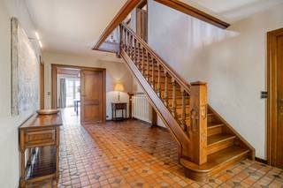 <h2><strong><strong>Karaktervolle villa met verwarmd zwembad, praktijkruimte en royale leefruimtes</strong></strong></h2><p>In het charmante Wespelaar, een groene deelgemeente van Haacht, bevindt zich deze stijlvolle villa op een royaal perceel van meer dan 21 are. Een woning met een uitzonderlijk gevoel van ruimte, veel privacy en tal van mogelijkheden. Gelegen vlak bij het centrum, op wandelafstand van winkels en het treinstation. Met een uitstekende verbinding naar Leuven en Mechelen combineert deze eigendom een rustige woonomgeving met een bijzonder vlotte bereikbaarheid.</p><p><br />De brede gevel en de imposante oprit geven de woning meteen een statige uitstraling. Achteraan ontvouwt zich een prachtig aangelegde tuin met veel privacy. Achter deze tuin bevindt zich het Arboretum, wat zorgt voor een bijzonder groene en rustige omgeving. Dankzij de zuidwestelijke oriëntatie geniet je hier volop van de zon: op het terras en aan het grote, verwarmde buitenzwembad. Dat zwembad wordt bovendien via een warmtepomp verwarmd, waardoor je het zwemseizoen moeiteloos kan verlengen. De ideale plek voor lange zomerdagen én -avonden.</p><p><br />Via de imposante inkomhal met gastentoilet betreed je de leefruimte die zonder twijfel het hart van de woning vormt. Met een oppervlakte van maar liefst 111 m² en een uitzonderlijke breedte van ongeveer 18 meter is dit een woonkamer van zeldzaam formaat. De terracotta tegelvloer en de houten balken aan het plafond geven de ruimte een uitgesproken karakter. Grote raampartijen zorgen voor een mooie lichtinval en verbinden het interieur met de tuin. Aansluitend bevindt zich de volledig ingerichte keuken met ruime eethoek. Vanuit de keuken is er toegang tot een praktische berging en de kelder.</p><p><br />Op de eerste verdieping, waar een parketvloer overal bijdraagt aan de warme sfeer, bevinden zich maar liefst vijf slaapkamers en twee badkamers. Alle ruimte dus voor een groot gezin, logeerkamers, hobbyruimtes of een extra bureau. Daarnaast beschikt de woning over bergkelders en zolderruimtes die extra opslagmogelijkheden bieden. Met een totale vloeroppervlakte van ongeveer 506 m², exclusief kelders, biedt deze villa een indrukwekkende hoeveelheid leefruimte.</p><p><br />Een bijzonder grote bijkomende troef is de praktijkruimte van ongeveer 50 m², die via een aparte inkom toegankelijk is. Deze beschikt over een eigen wachtruimte en sanitair en leent zich perfect voor vrije beroepen, zelfstandigen of ondernemers die wonen en werken willen combineren. Tegelijk biedt deze indeling interessante mogelijkheden voor zorg- of kangoeroewonen.</p><p><br />De woning behaalt een EPC-label C en tegelijk biedt de energieprestatie nog mogelijkheden voor verdere optimalisatie, voor wie de woning naar eigen smaak en comfortniveau wil moderniseren. De elektrische installatie is momenteel niet conform, maar kan volgens raming met een beperkte kost van ongeveer €3.000 in orde worden gebracht.</p><p><br />Kortom, een eigendom waar ruimte, privacy en functionaliteit samenkomen op een bijzonder groen perceel. Interesse om deze woning zelf te ontdekken? Geef JES dan gerust een seintje en we plannen graag een bezoekmoment in.</p><figure><div></div></figure><p></p>