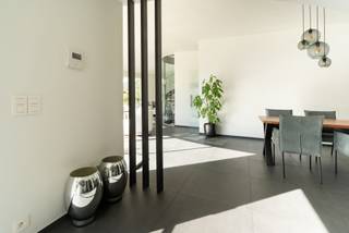 <p>Wonen in harmonie met de natuur. Deze unieke, recent geactualiseerde woning is ontworpen om het prachtige bosgebied en de vijver naadloos te integreren in uw dagelijks leven. Met een overvloed aan natuurlijk licht en vier comfortabele slaapkamers biedt deze woning een oase van rust en sereniteit. Ontsnap aan de drukte en omarm de schoonheid van uw eigen privédomein.<br /><br />De woning is ontworpen door het gekende Architectenbureau Luc Denis uit Antwerpen. De natuurlijke vijver en het omringende bos was voor de architect aanleiding een hoofverblijf met een ronde vorm te creëren met daaraan een rechthoekige uitbouw met de ruimtes die aanvullend aan de woonfunctie zijn. <br /><br />De woning is toegankelijk via de centrale inkomhal. De inkomhal is voorzien van een spiltrap uitgevoerd met transparante treden. Door de dakkoepel in het zinken dak treedt het licht hier op een subtiele manier binnen. Aan de rechterzijde de eerste kamer. Oorspronkelijk ontworpen als atelier maar uitstekend bruikbaar als slaapkamer of thuiskantoor. Deze ruimte heeft een eigen uitgang naar buiten. Daarnaast een vestiairekast, toegang tot het gastentoilet en de kelder.<br /><br />De kelder is via een vaste trap bereikbaar. In de kelder, met een oppervlakte van ca. 24m², de nutsvoorzieningen en de omvormer met batterijen voor de zonnenstroominstallatie.<br /><br />De trap geeft toegang tot de cirkelvormige verdieping. Op de verdieping 2 badkamers, 3 ruime slaapkamers en een ruime was-, en strijkruimte. De badkamers voorzien van toilet en inloopdouche. De hoofdbadkamer voorzien van een zogenaamd Japans toilet.<br /><br />Terug naar het gelijkvloers. Via de glazen deur toegang tot de leefruimte met eethoek, zithoek en tv-hoek. Totaal oppervlakte ca. 70m². Aansluitend de veranda met een oppervlakte van ca. 21m². De veranda is door een glaspartij afgesloten van de tv-hoek en heeft volledig zicht over de vijver en het achterliggende bos. De tv-hoek kent een hoofdzakelijk dichte wand waardoor een besloten sfeer wordt gecreëerd, De zithoek kijkt uit over het houten terras en de vijver naar het achterliggende bos. De waardevolle moerascipres (Taxodium distichum) is een parel aan de rand van de vijver en geeft in de zomer een aangename filtering van de zon met behoud van het licht. Aan de zithoek de eethoek en aansluitend de keuken. <br /><br />De eethoek meet ca. 24m², de keuken is volledig nieuw en heeft een moderne uitstraling. Vanuit de keuken toegang tot 2 bergingen van ca. 6 en 12m². In de achterste berging bevindt zich ook de verwarmingsinstallatie. De woning wordt verwarmd door middel van een condenserende HR-ketel op gas en heeft op het gehele gelijkvloers vloerverwarming. Terug naar de keuken toegang tot de extra badkamer met toilet en de deur naar de dubbele carport. De carport heeft een oppervlakte van ca. 36m². De woning is voorzien van een centraal stofafzuigsysteem.<br /><br />Op het dak 29 zonnepanelen van elk 405Wp geplaatst in 4 strings voor maximale opbrengst. De zonnepanelen gekoppeld aan 6 accu’s met een totale opslagcapaciteit van 20kWh. Aan de carportzijde is een laadpaal geplaatst voor het opladen van de elektrische wagens. De EPC-waarde is een uitstekende waarde voor de woning maar is nog niet aangepast met deze wijzigingen en de woning zal dus nog een stuk beter resultaat laten zien.<br /><br />Recent is er een extra overkapping gebouwd met een oppervlakte van ca. 33m². Vanaf de veranda is de woning voorzien van een houten terras met aansluitend een loopbrug. In de tuin wordt op korte termijn nog een complete louncheruimte opgericht.</p>
<p>De tuin en de vijver zijn goed onderhouden en de woning is instapkaart. Benieuwd naar deze bijzondere woning in de groene en rustgevende omgeving van Kalmthout? Bel gerust voor een uitgebreid bezoek. Via 03 240 11 99 is een afspraak snel gemaakt.</p>