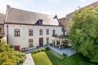 <p>Découvrez cet hôtel de maître situé en plein cœur de la ville, sur un terrain de 4a88, avec une surface habitable de 450 m². Cette demeure authentique allie charme intemporel et luxe moderne, offrant une expérience de vie unique.</p>
<p>Le bien est exempt d’amiante, dispose d’un certificat énergétique de classe D et l’installation électrique est conforme !</p>
<p>Dès l’entrée, vous êtes accueilli par un hall élégant et un vaste espace de vie avec cheminée. La maison se distingue par ses magnifiques sols en parquet et en travertin, ses hauts plafonds et ses éléments authentiques. La cuisine haut de gamme est un véritable rêve pour tout amateur de cuisine.<br />Au rez-de-chaussée, vous trouverez également un second salon et un bureau, idéal pour l’exercice d’une profession libérale.</p>
<p>Le premier étage comprend quatre chambres spacieuses, dont une suite parentale avec salle de bains attenante et accès à la terrasse sur le toit. Une deuxième salle de bains et un dressing complètent le confort.</p>
<p>Le grenier de 100 m² est entièrement aménagé en espace de vie et dispose de toutes les commodités.</p>
<p>À l’extérieur, vous profitez de plusieurs terrasses et d’un magnifique jardin avec pavillon de jardin, idéal pour des soirées d’été conviviales, des fêtes en plein air ou simplement pour se détendre dans votre propre oasis de verdure.</p>
<p>Une double place de parking à distance de marche (résidence Menegaard) est disponible en option.</p>
