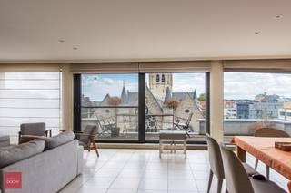 PENTHOUSE bestaande uit een ruime inkomhal, living, eetplaats en keuken met zicht op de kerk/markt, 2 bergingen, 3 slaapkamers, 2 badkamers, dressing, terrassen vooraan en achteraan, een autostandplaats en kelderberging. Mogelijkheid 2e autostandplaats bij te kopen. Opp. 184m²