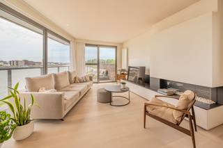 <p>Ontdek deze uitzonderlijk afgewerkte penthouse op een unieke locatie aan het water in Willebroek. Dankzij de grote raampartijen baadt het appartement de hele dag in natuurlijk licht en geniet u van een prachtig ruimtelijk gevoel.</p><p>Via de ruime inkomhal, voorzien van een stijlvolle ingebouwde vestiairekast, betreedt u deze luxueuze woonst. De lichtrijke leefruimte vormt het hart van de penthouse en geeft rechtstreeks uit op het royale, zuidgerichte terras waar u in alle rust kunt genieten van zon en uitzicht op het water. De leefruimte is afgewerkt met hoogwaardige parketvloeren, maatwerk kasten en een elegante ingebouwde gashaard die zorgt voor extra sfeer en comfort.</p><p>Aansluitend bevindt zich de open, volledig geïnstalleerde leefkeuken die naadloos overgaat in de woonruimte. Deze moderne keuken is uitgerust met kwalitatieve toestellen en beschikt bovendien over een geïntegreerde wijnkoeler, ideaal voor liefhebbers van gastronomie en gezelligheid.</p><p>De penthouse biedt twee volwaardige slaapkamers en een aparte walk-in dressing. De klasse volle badkamer is voorzien van een ligbad, ruime inloopdouche en een stijlvolle lavabo met hoogwaardig badkamermeubel.</p><p>Verder beschikt de woning over een praktische berging en een afzonderlijk gastentoilet.</p><p>Deze exclusieve penthouse combineert een toplocatie aan het water met een hoogwaardige afwerking, royale leefruimtes en een overvloed aan natuurlijk licht. Een unieke woonkans voor wie op zoek is naar comfort, luxe en uitstraling op een uitstekende locatie in Willebroek.</p><p></p><p>Het appartement is uiterlijk 1 december 2026 beschikbaar. <br />Stedenbouwkundige inlichtingen aangevraagd. </p><p>Dit pand wordt verkocht onder het stelsel van erfpacht. U koopt het appartement, kelderberging en autostaanplaats zelf, maar huurt de ondergrond. De canon (jaarlijkse vergoeding voor de grond) bedraagt +/- 1200€/jaar. Het erfpachtcontract loop tot en met 17/03/2107.</p>