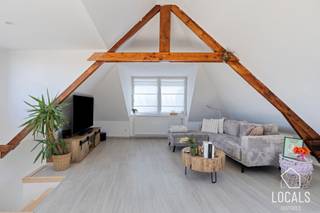 In het landelijke Zarlardinge bevindt zich dit verrassend ruime en instapklare duplexappartement met aparte privatieve ingang. De woonst combineert een praktische indeling met veel lichtinval en een warme, karaktervolle uitstraling dankzij de zichtbare houten dakstructuur. Via de afzonderlijke inkomhal kom je binnen in het appartement, waarna de trap je naar de nachthal brengt. Het appartement biedt een verzorgde badkamer met ligbad, inloopdouche en dubbele lavabo, een toilet en een praktische wasruimte. De verschillende kamers kunnen flexibel worden ingericht als slaapkamer, dressing, bureau of hobbyruimte, waardoor de woning zich perfect aanpast aan verschillende woonbehoeften.<br />Op de hoogste verdieping kan u de leefruimte terugvinden. Deze vormt het hart van de woning en biedt plaats voor een gezellige zithoek, een eetgedeelte en een volledig ingerichte open keuken. De grote ramen en dakvensters zorgen voor een aangenaam open gevoel, terwijl de authentieke houten balken extra charme toevoegen.<br />De keuken is ruim opgevat en beschikt over veel werk- en opbergruimte. Dankzij de neutrale afwerking, lichte vloeren en goed onderhouden staat is dit appartement volledig instapklaar. Een ideale woonst voor wie op zoek is naar ruimte, comfort en karakter op een centrale locatie, met het bijkomende voordeel van een volledig aparte ingang.<br />Kom jij graag deze eigendom bezoeken? Mail dan naar info@localsvastgoed.be of bel naar 054 23 53 83.