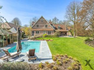 In de residentiële wijk ‘Den Drijhoek’ te Schilde, een buurt die bekendstaat om haar rustige en groene karakter bevindt zich deze indrukwekkende villa op een royaal perceel. Bij het betreden van de woning via de elegante inkomhal met gastentoilet, wordt u direct omarmd door een sfeer van tijdloze klasse. De royale L-vormige leefruimte ademt karakter dankzij de massieve parketvloer, authentieke balkenpartijen en sfeervolle haarden.
Aansluitend vindt u de droom van elke culinaire liefhebber: een hyper-uitgeruste keuken waar enkel genoegen is genomen met het beste. Terwijl de knalrode elektrische AGA de show steelt, zorgen de Sub-Zero koel-vriescombinatie en het keukeneiland met wijnkoeler en professionele wokplaat voor een gastronomische ervaring op topniveau.
Het doordachte ontwerp biedt u het comfort van een grote slaapkamer op het gelijkvloers met aparte toegang van buiten. Vanuit deze slaapkamer ontwaakt u met een rustgevend uitzicht op de tuin en het zwembad, terwijl de dressing met maatwerk en de en-suite badkamer met inloopdouche een gevoel van hotelsuite-luxe geven.
Op de verdieping leidt een riante overloop naar een master suite met en-suite badkamer en nog 3 royale slaapkamers. Een derde badkamer en een separate wasplaats vervolledigen dit niveau.
Buiten transformeert het perceel in een private oase. Het verwarmde zwembad wordt omringd door zonneterrassen, overdekte terrassen en een sfeervolle patio met buitenhaard, de ideale plek voor lange zomeravonden. Deze villa is technisch klaar voor de toekomst met zonnepanelen, airco, camerabewaking, een oplaadpunt voor elektrische wagens en tuinberegening. Een dubbele garage en een koele wijnkelder maken dit unieke plaatje compleet. Een residentie waar luxe, veiligheid en leefplezier elkaar ontmoeten. Plan vandaag nog uw bezoek in en laat u betoveren door deze prachtige woning.